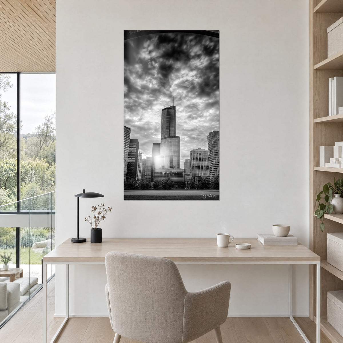 Wall art of the spire of a glass tower in the light, black clouds and pearl grey, hung above a light wood desk