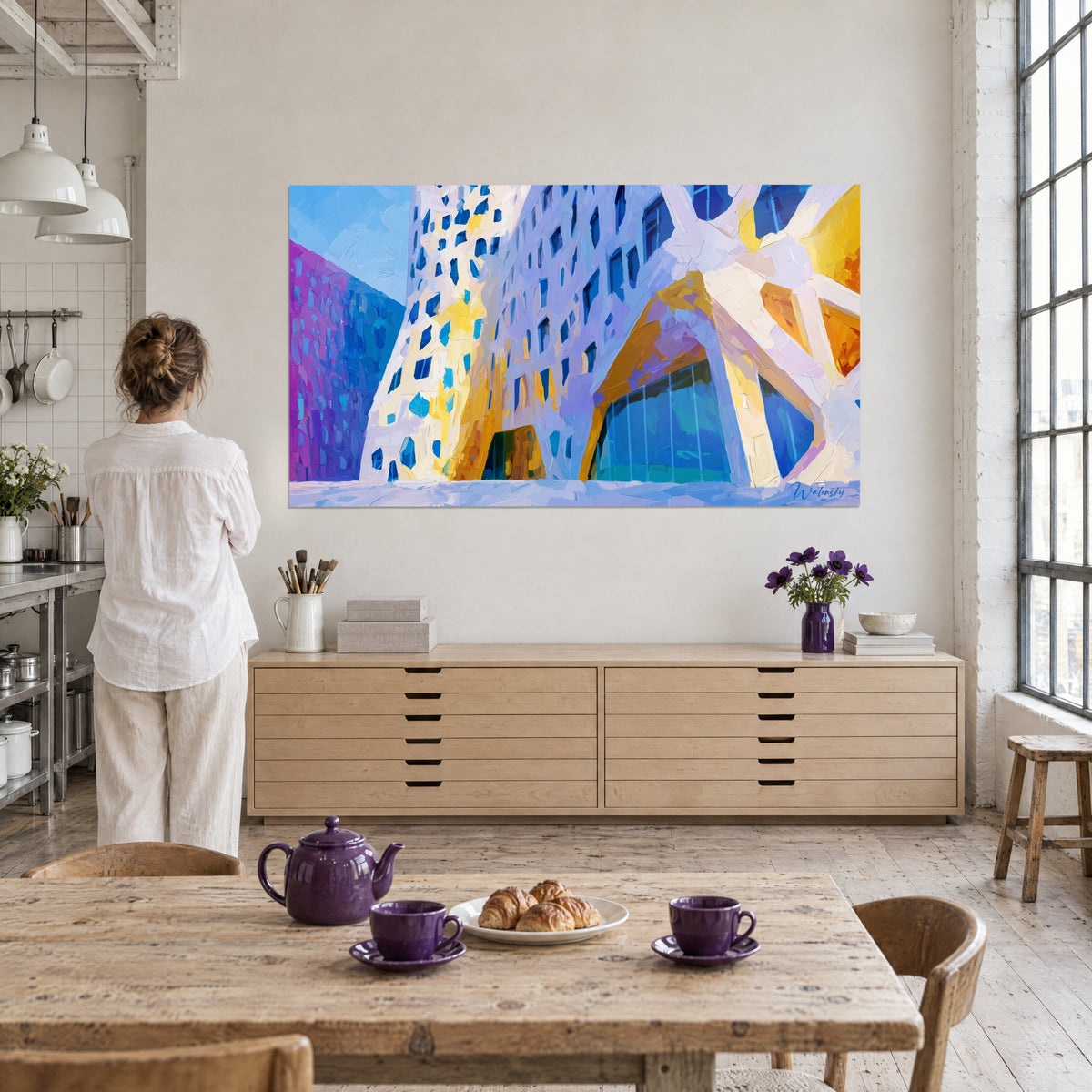 Cuadro edificio futurista en pinceladas de espátula lavanda y amarillo dorado, ventanas azules, mujer de espaldas frente a la pared de un loft luminoso