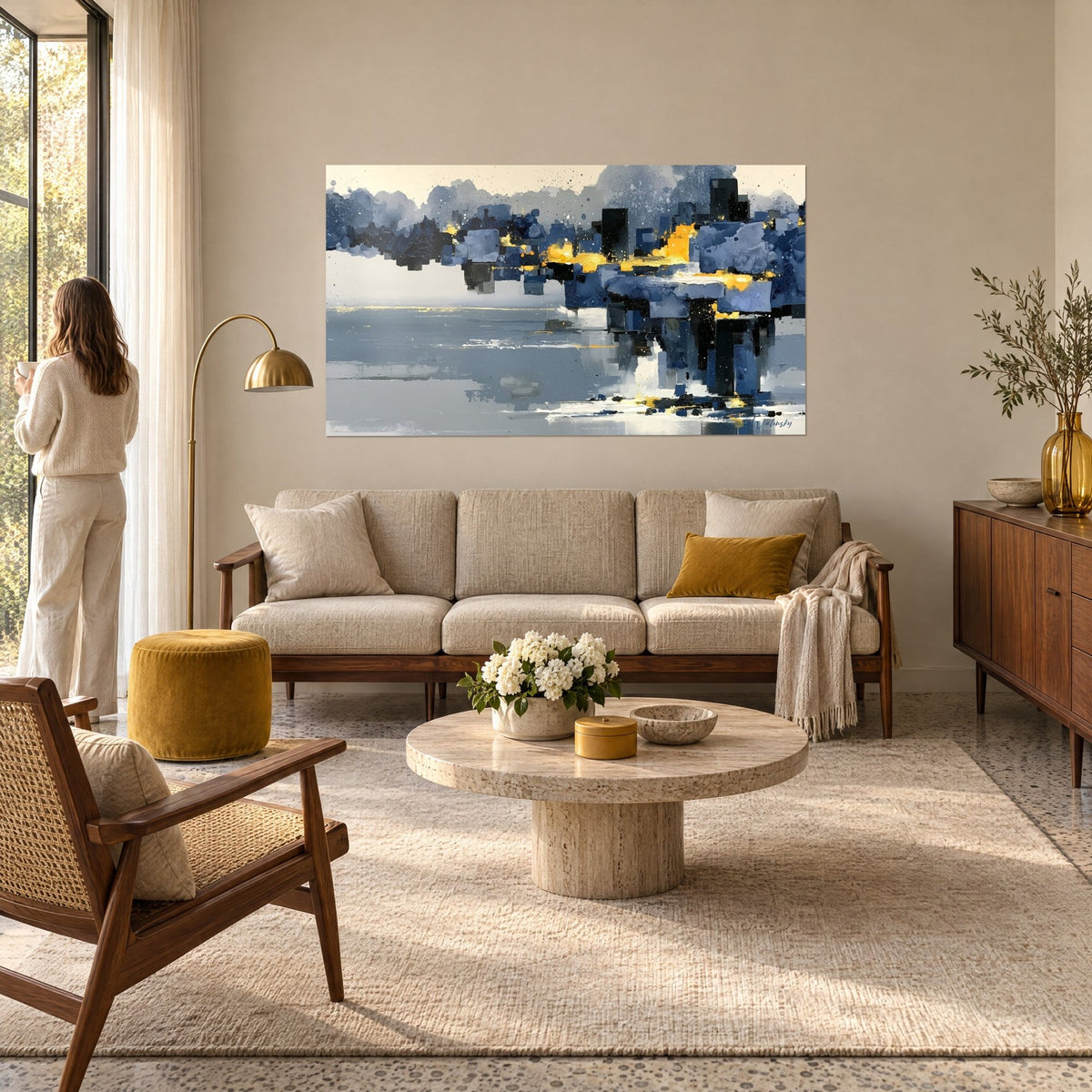 Tableau skyline abstrait aux blocs bleu ardoise et touches d'or, reflet gris sur l'eau, au-dessus d'un canapé dans un salon lumineux