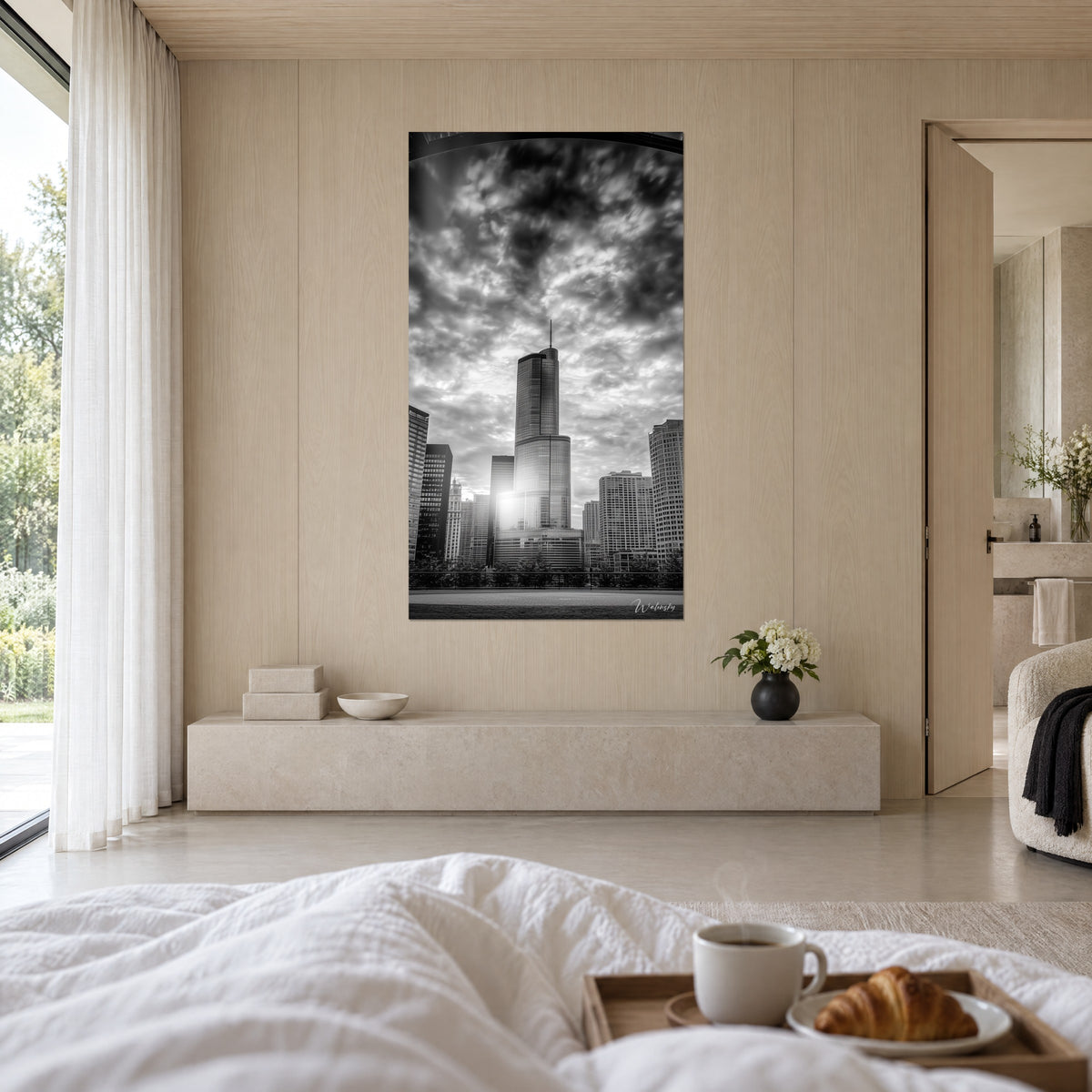 Wall art of a slender high-rise and dark clouds, charcoal grey and luminous white with a sun glare, hung above a bed in a light bedroom