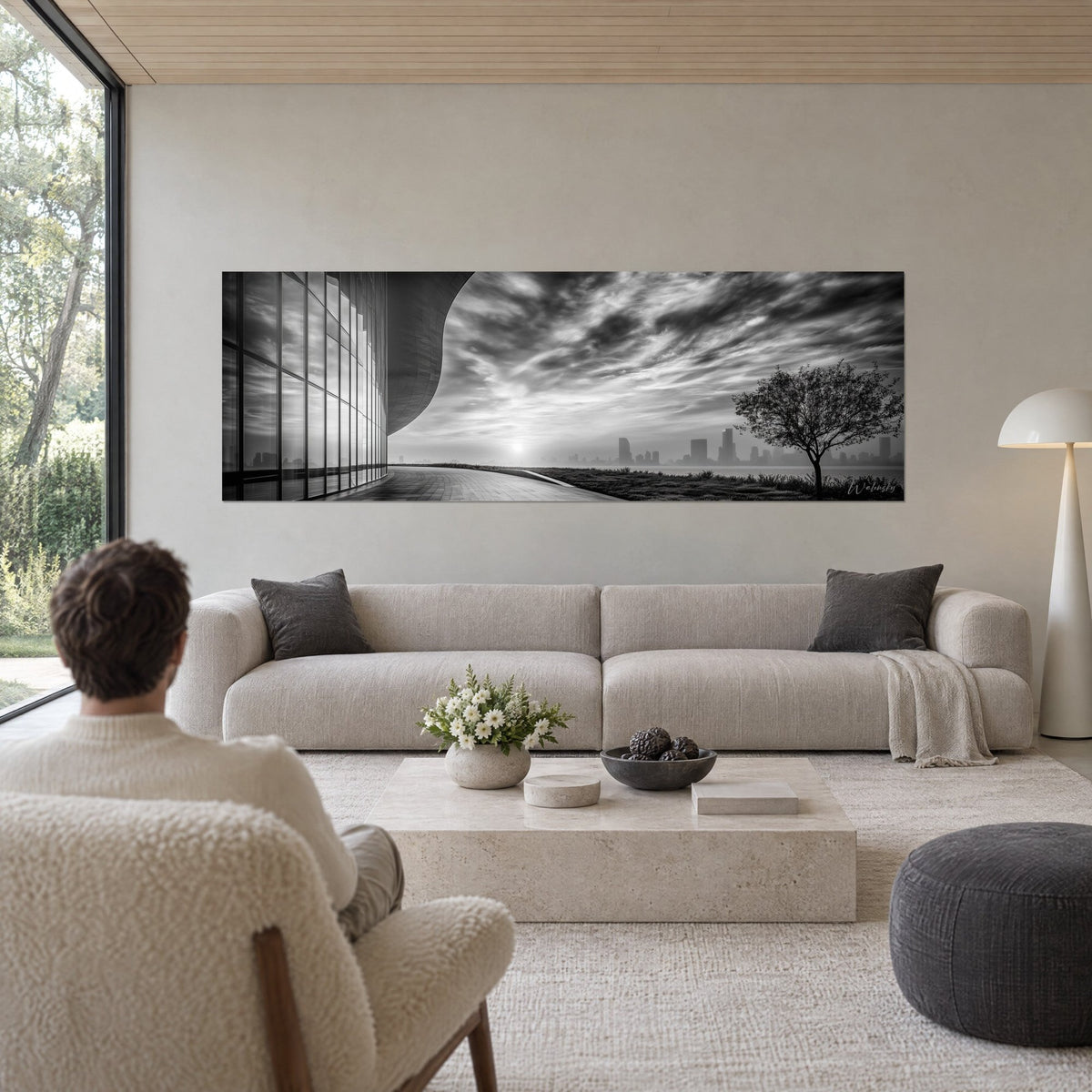 Tableau panoramique d'architecture courbe en noir et blanc, ciel strié de nuages gris et blancs, au-dessus d'un canapé dans un salon lumineux