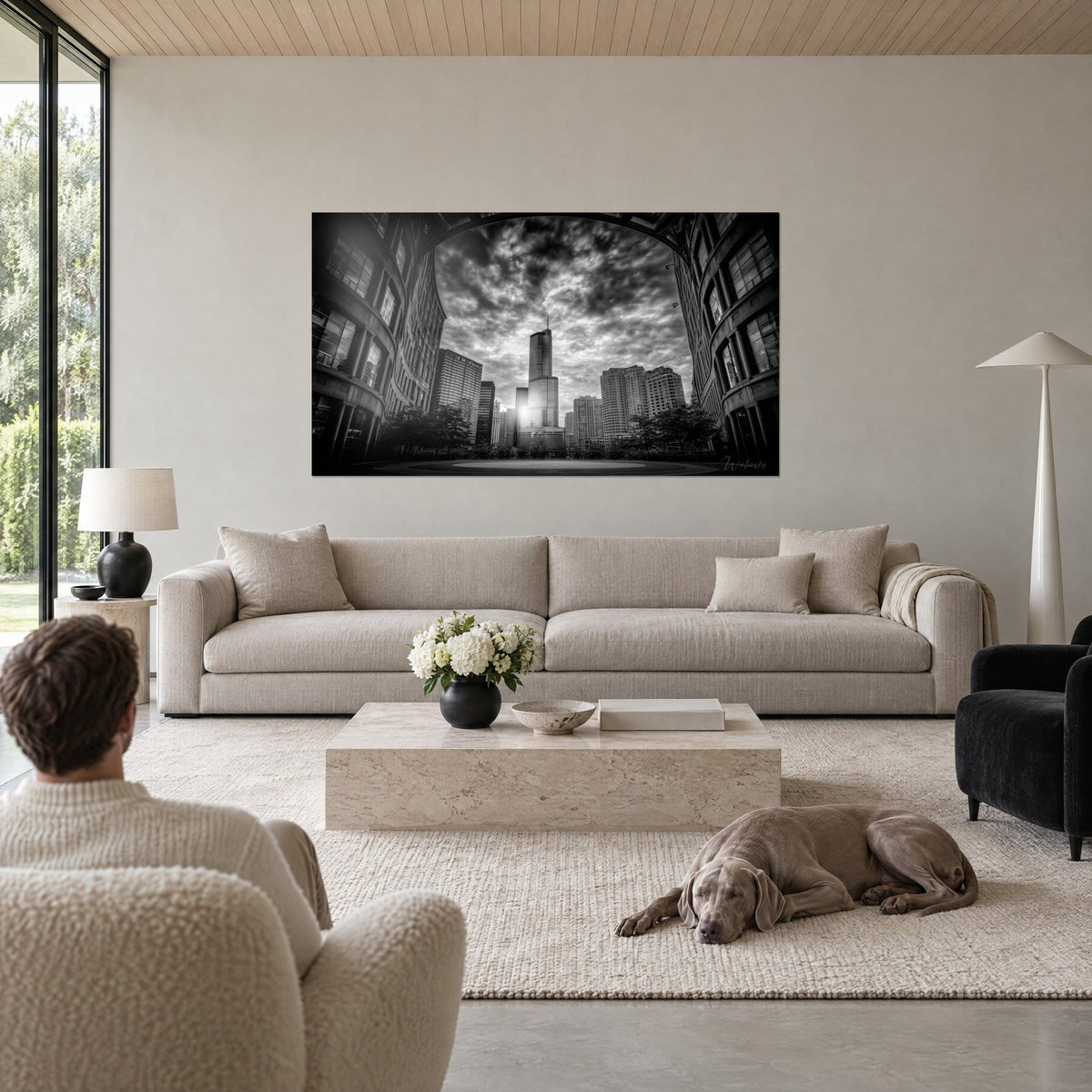Tableau gratte-ciel de verre éclairé en contre-jour, ciel d'orage gris et blanc, deux personnes de dos, Weimaraner couché, au-dessus d'un canapé dans un salon lumineux