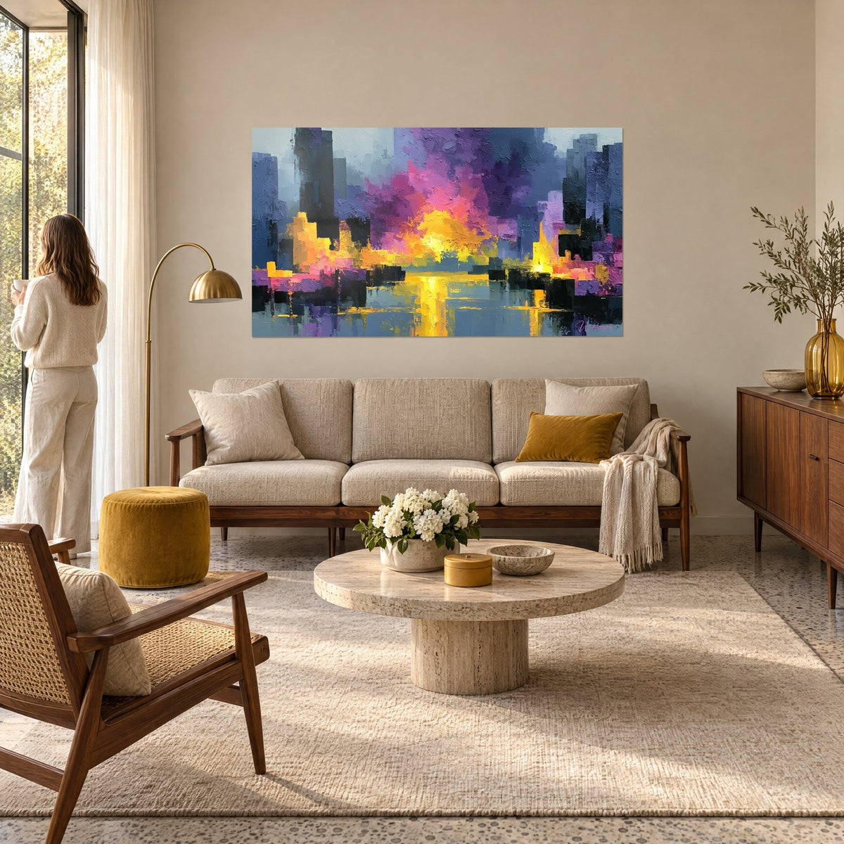 Tableau cité abstraite embrasée de jaune et de rose, tours bleu ardoise, au-dessus d'un canapé dans un salon lumineux