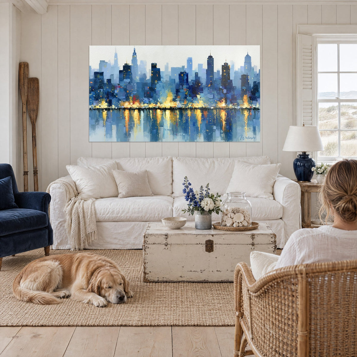 Tableau skyline de gratte-ciel bleu nuit aux reflets dorés, retriever couché sur le tapis, au-dessus d'un canapé dans un salon lumineux