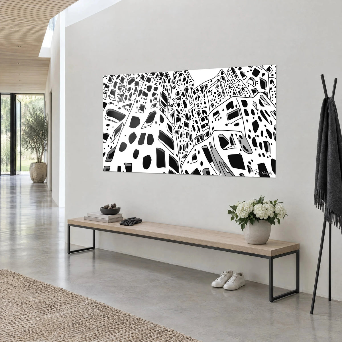 Wall art of facades dotted with dark windows, thick black outlines and white skies, hung above a bench in light wood and black metal