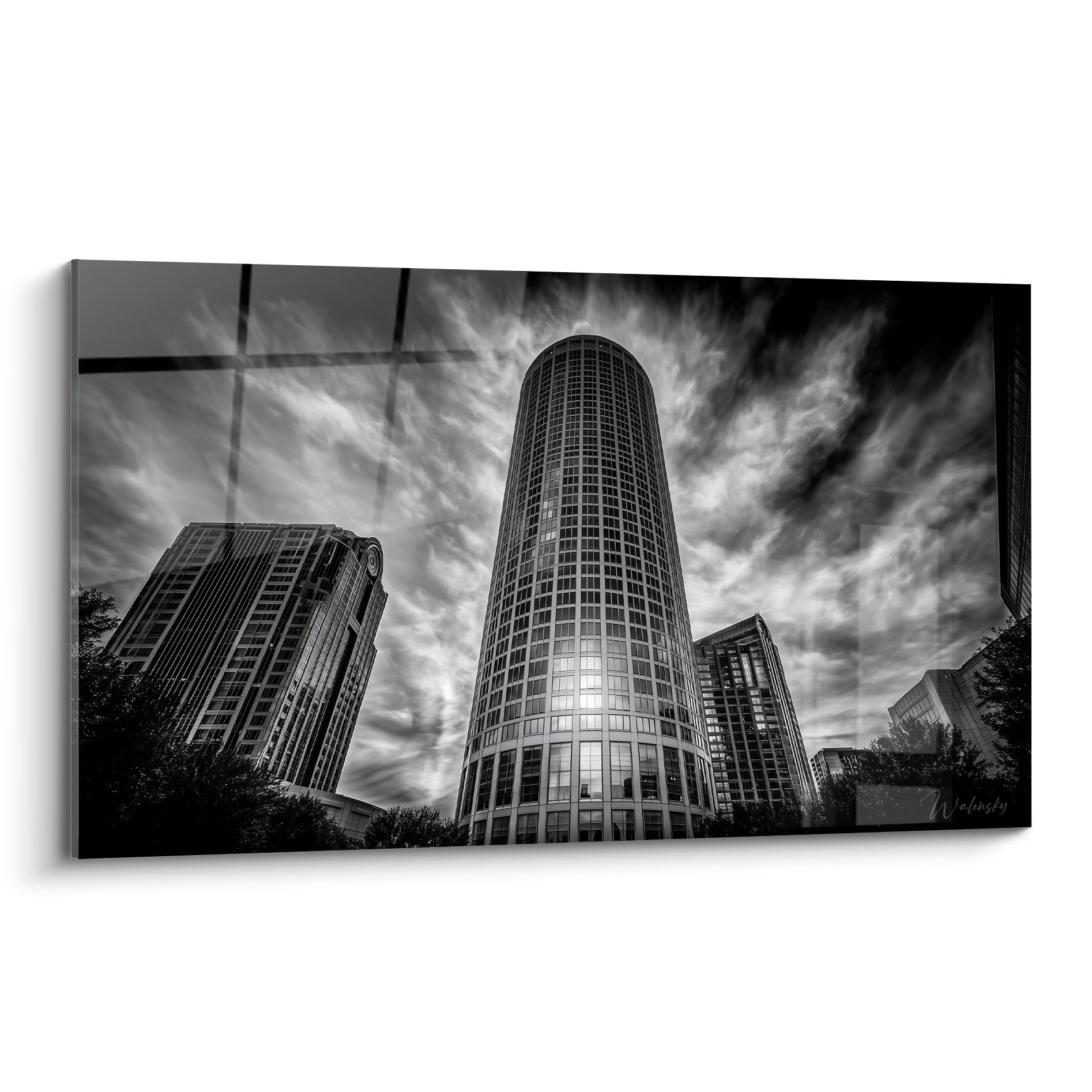 Gratte-ciel cylindrique noir et blanc sous un ciel nuageux dramatique, tour en verre et acier