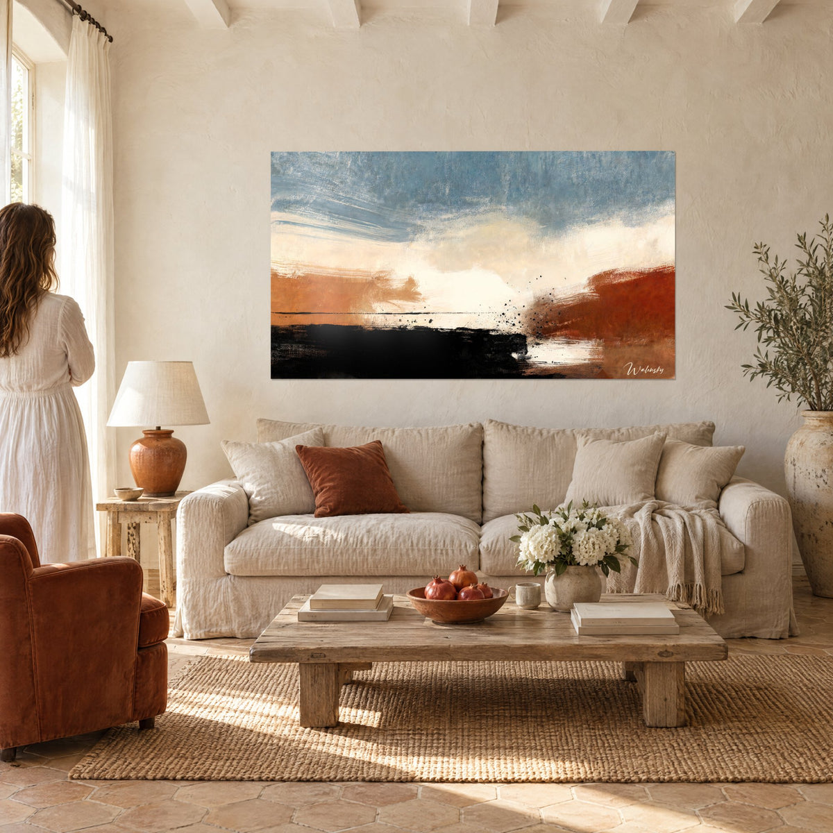 Tableau horizon abstrait aux nuages crème, bandes terracotta et noir profond, couple de dos, au-dessus d'un canapé dans un salon lumineux