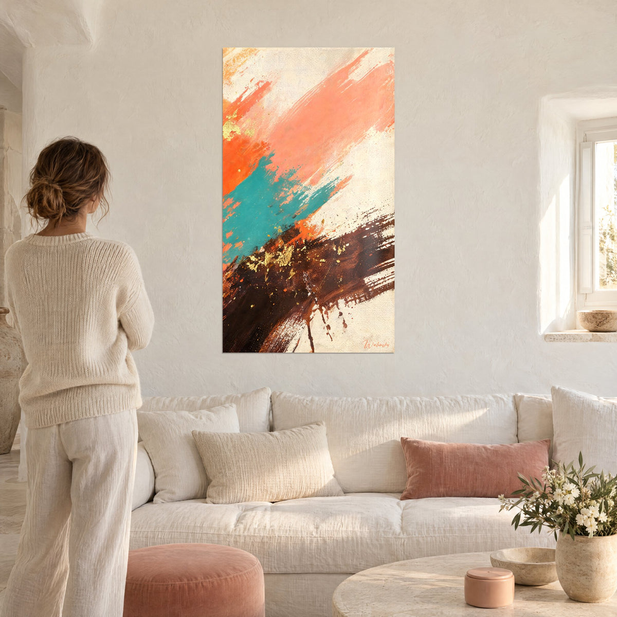 Tableau coulée corail et brune aux paillettes d'or, touche turquoise, regardée par une femme, au-dessus d'un canapé dans un salon lumineux