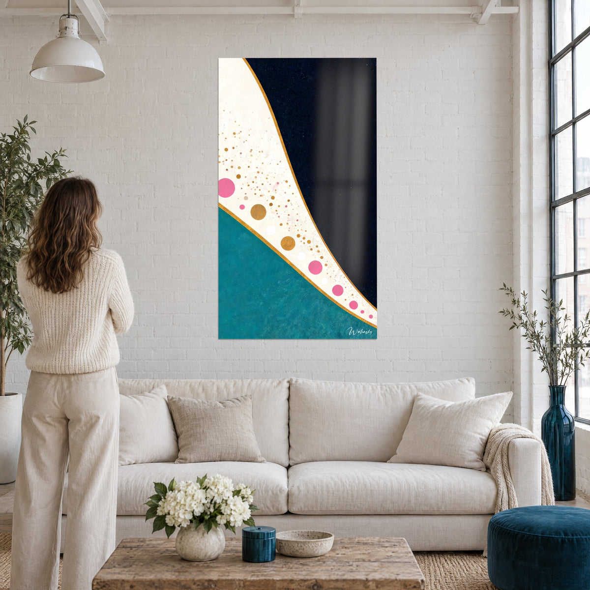 Quadro curva dorata che separa antracite e sarcelle, bolle rosa e oro, sopra un divano in un soggiorno luminoso