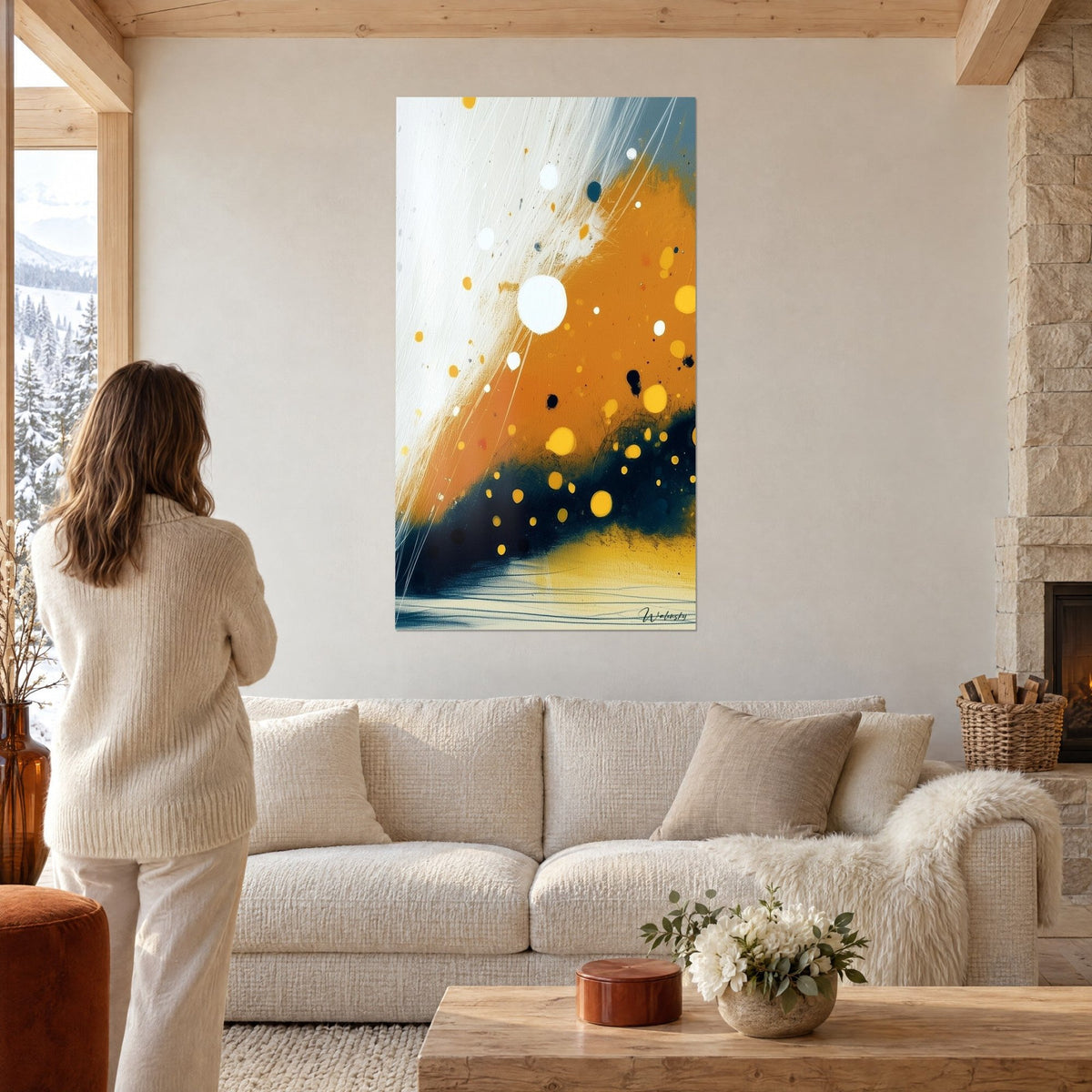 Tableau abstrait diagonale orange et blanche piquetée de gouttes jaunes, femme de dos, au-dessus d'un canapé dans un salon lumineux