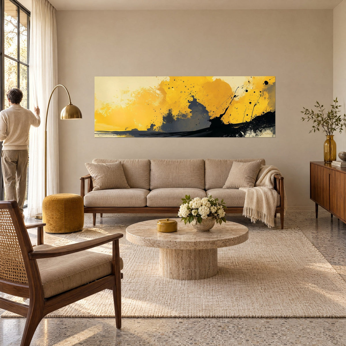 Tableau éclaboussures ocre jaune sur fond crème, masse grise et traînée noire, un homme de dos, au-dessus d'un canapé dans un salon lumineux