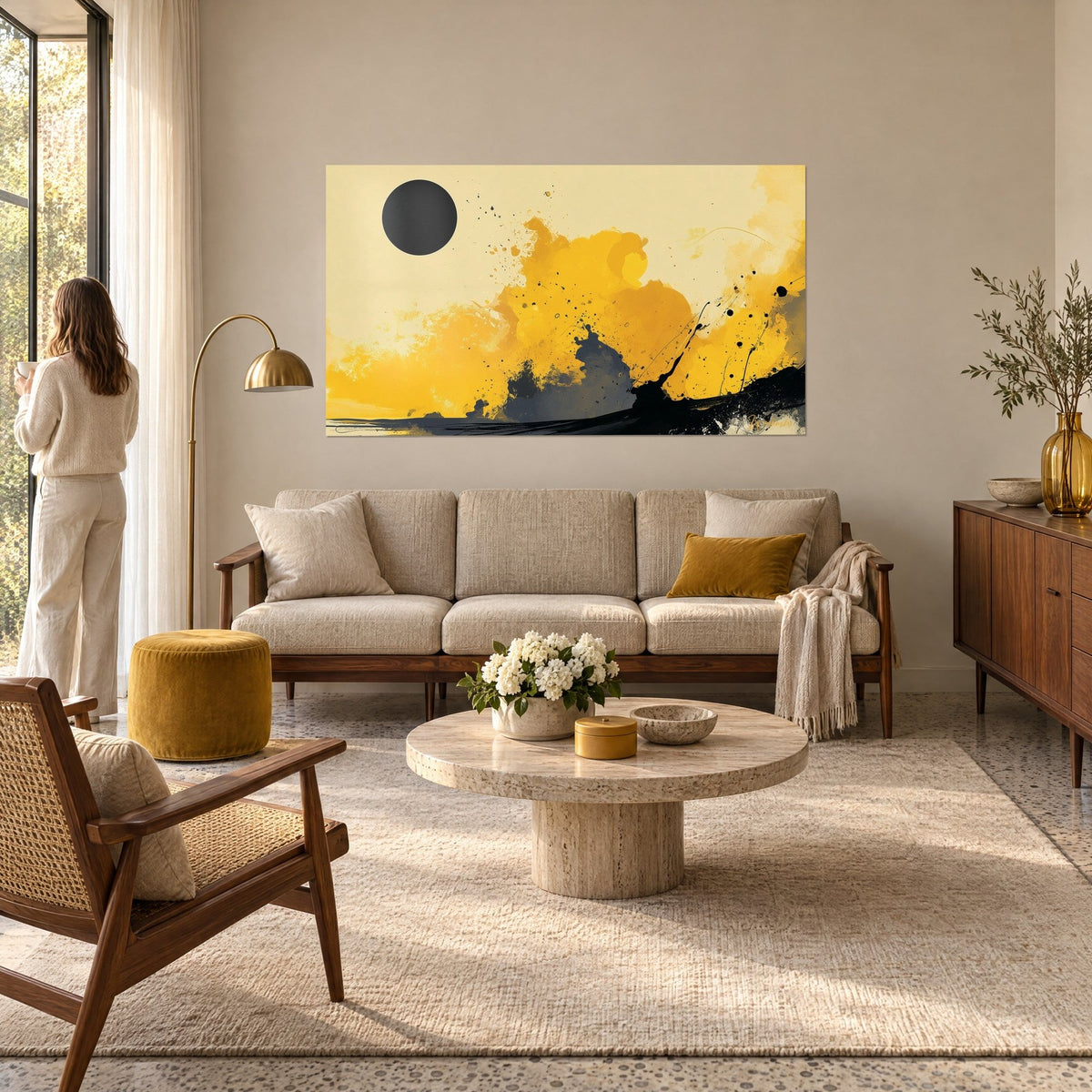 Tableau éclipse abstraite, disque noir sur nuées jaune moutarde et fond crème, femme de dos, au-dessus d'un canapé dans un salon lumineux