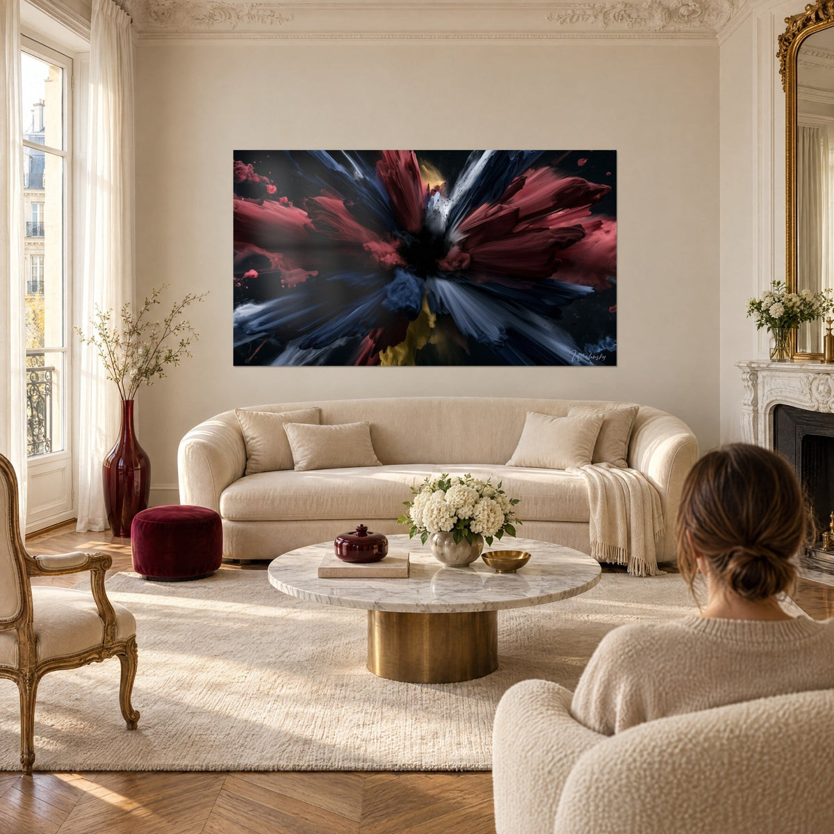 Quadro con petali che sbocciano in cremisi e blu notte su fondo nero, una donna di spalle sopra un divano in un soggiorno luminoso