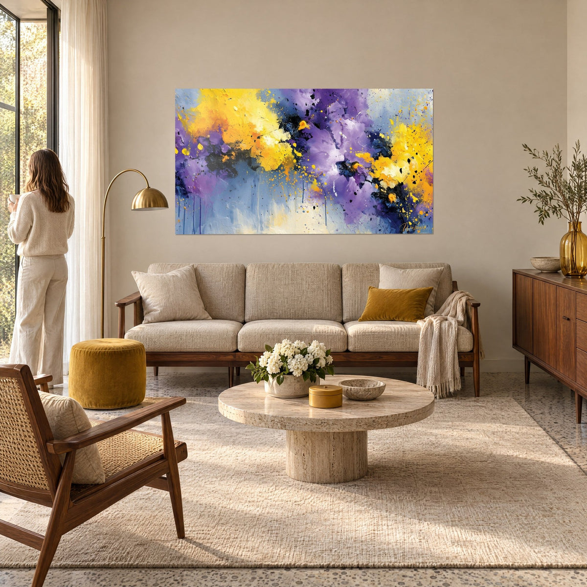 Tableau explosion de jaune citron et de violet éclaboussée de gouttelettes noires, femme de dos, au-dessus d'un canapé dans un salon lumineux
