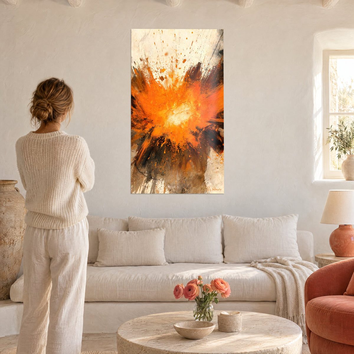 Tableau déflagration orange aux éclaboussures noires et noyau blanc, femme de dos, au-dessus d'un canapé dans un salon lumineux