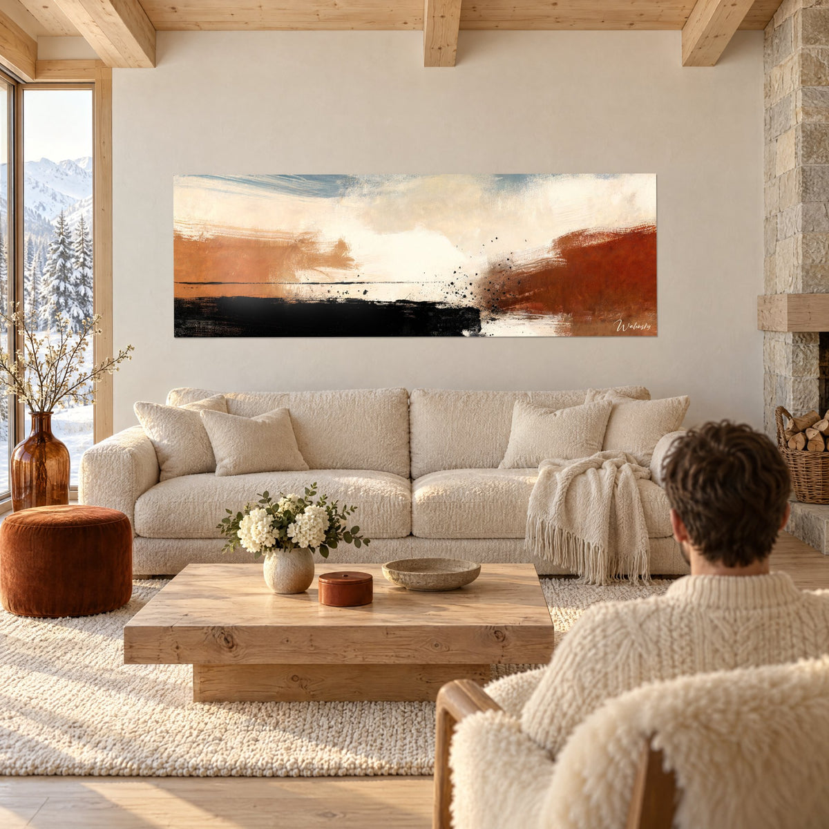 Tableau paysage abstrait ocre et rouille, bande noire en bas, vu par un couple de dos au-dessus d'un canapé dans un salon lumineux