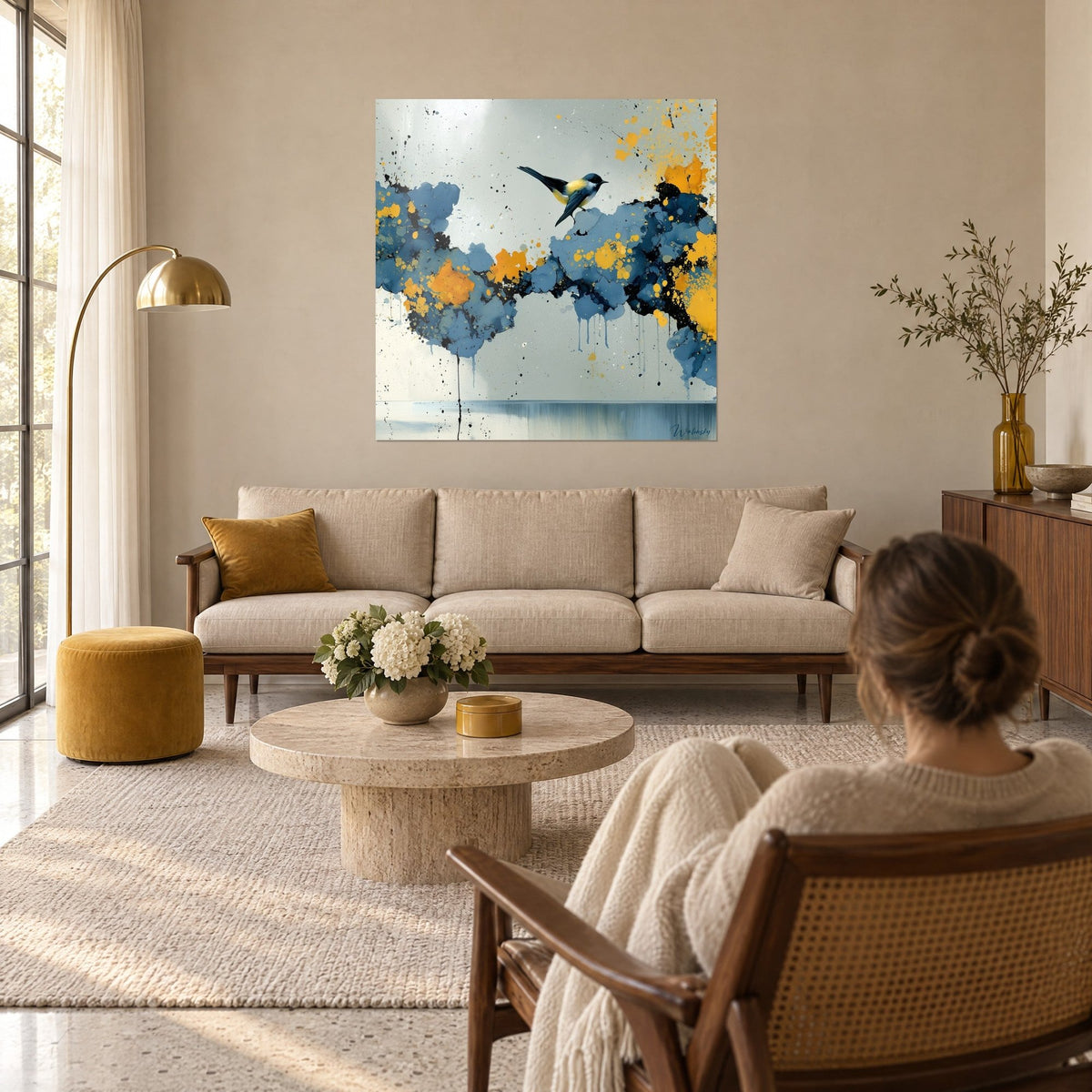 Wall art blue tit with a yellow belly, ochre and steel blue smudges, beige sofa, hanging above a sofa in a bright living room