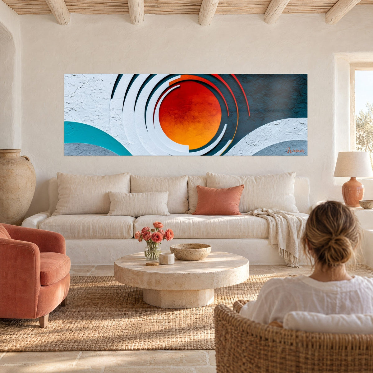 Cuadro sol naranja rodeado de anillos blancos en relieve sobre fondo azul petróleo, mujer de espaldas, encima de un sofá en un salón luminoso