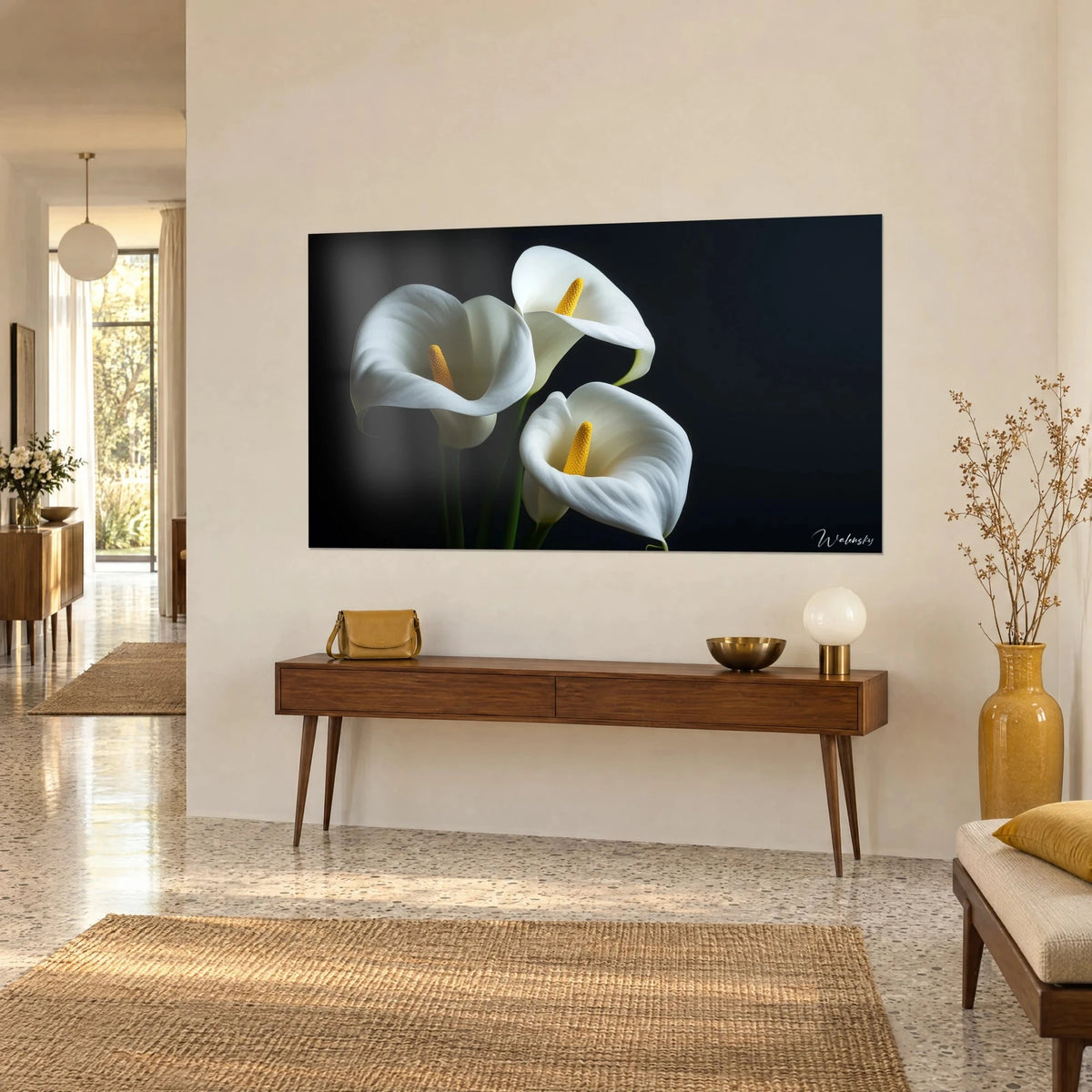 Tableau fleurs de calla aux spathes ivoire et spadices dorés sur fond noir, en vue de trois-quarts au-dessus d'une console en bois