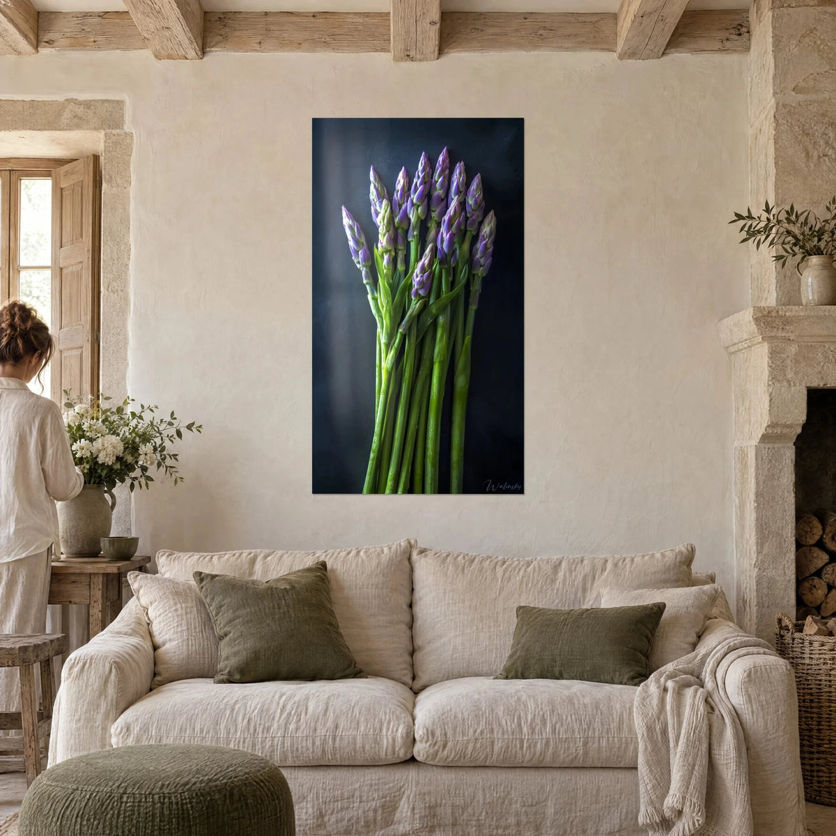 Quadro mazzo di punte di asparagi viola con teste lilla e steli verde tenue su fondo grigio ardesia, sopra un divano in un soggiorno luminoso