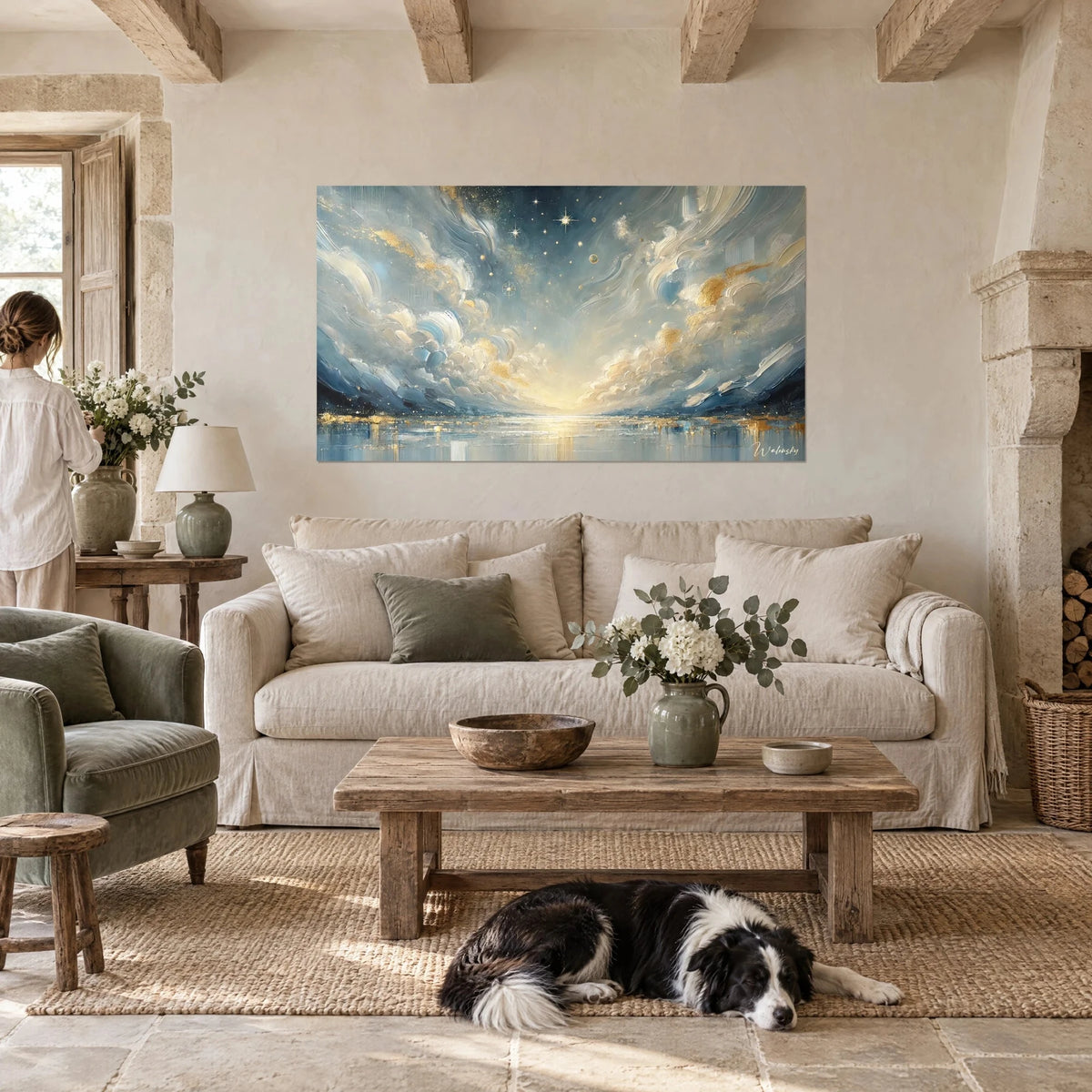 Wall art starry sky in steel blue and gold, a woman seen from behind and a collie above a sofa in a bright living room