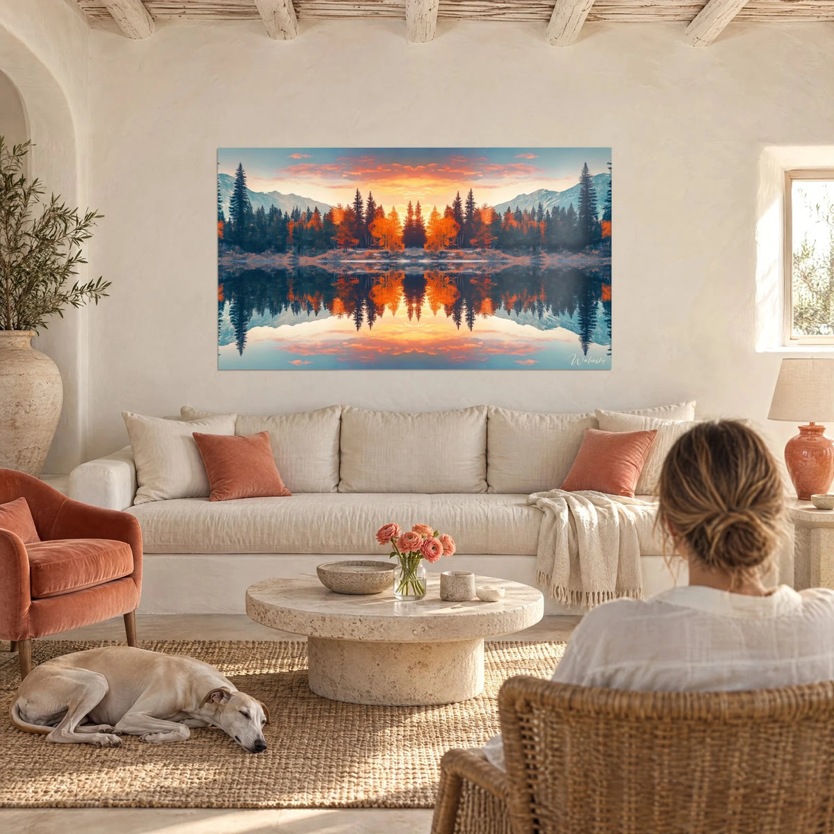 Cuadro bosque otoñal reflejado en un lago, alerces naranjas y abetos verdiazules, sobre un sofá en un salón luminoso