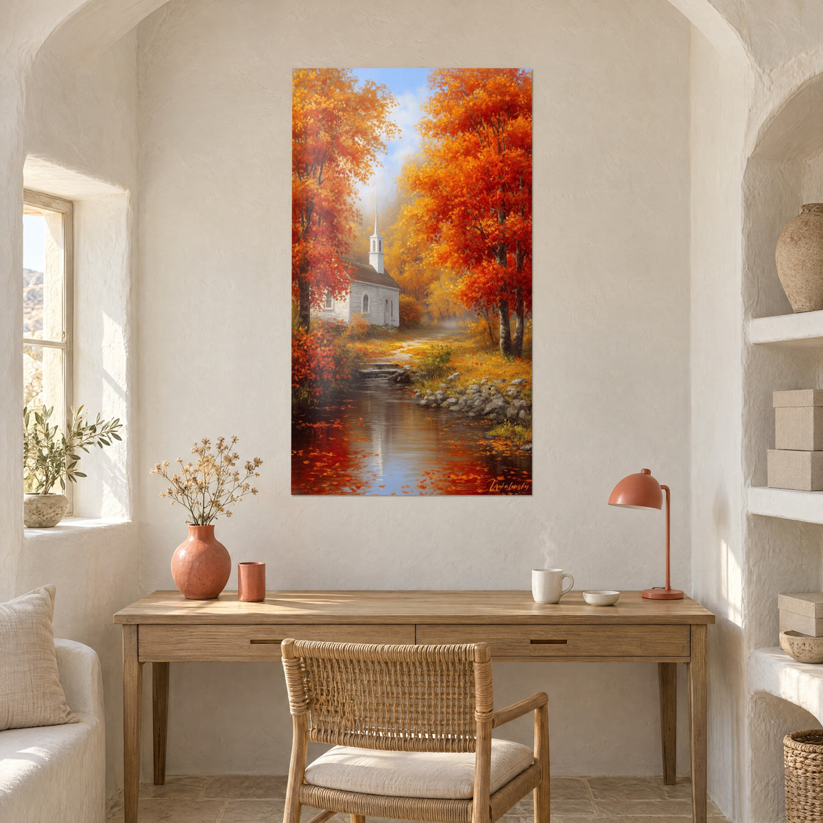 Wall art autumn landscape with white chapel, vivid red foliage and pale blue sky, hung above a light wood desk