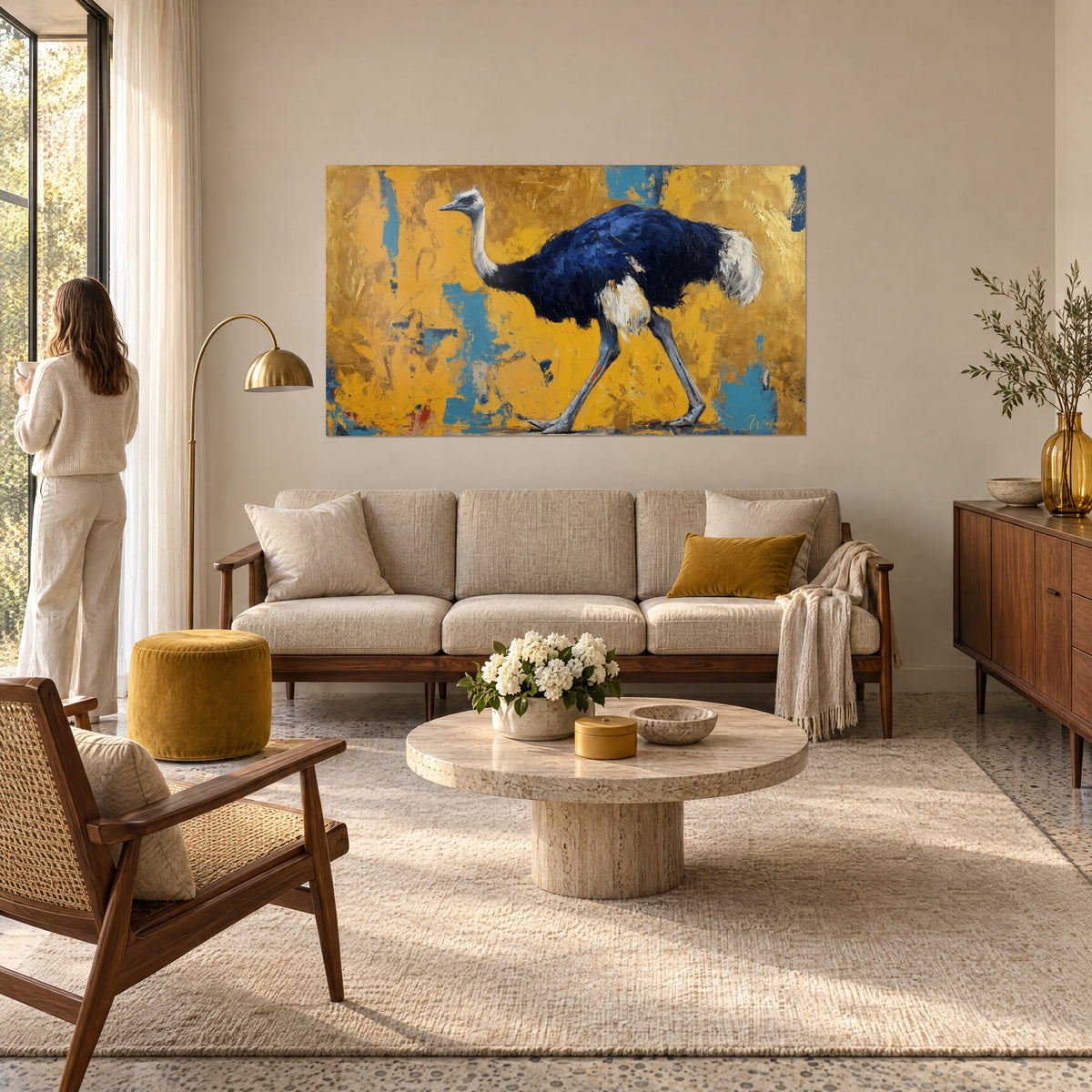 Tableau autruche au plumage bleu marine et cou blanc, fond jaune ocre, une femme de dos au-dessus d'un canapé dans un salon lumineux