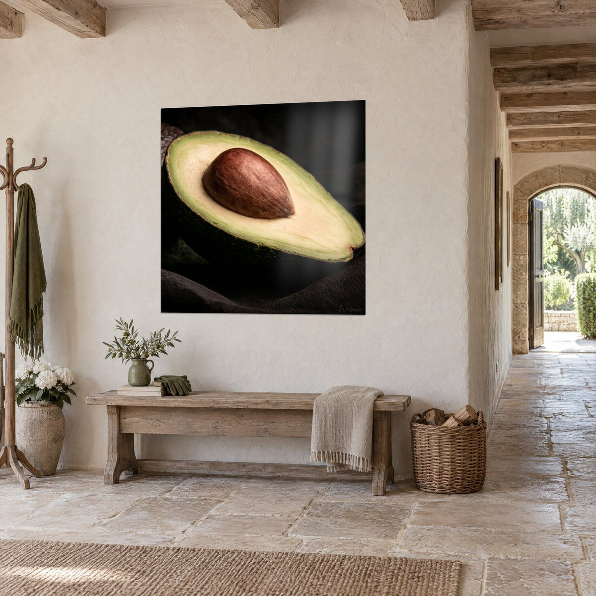 Wall art fruit cut in half, pale green flesh and chestnut pit, hung in a stone hallway beside a wooden bench