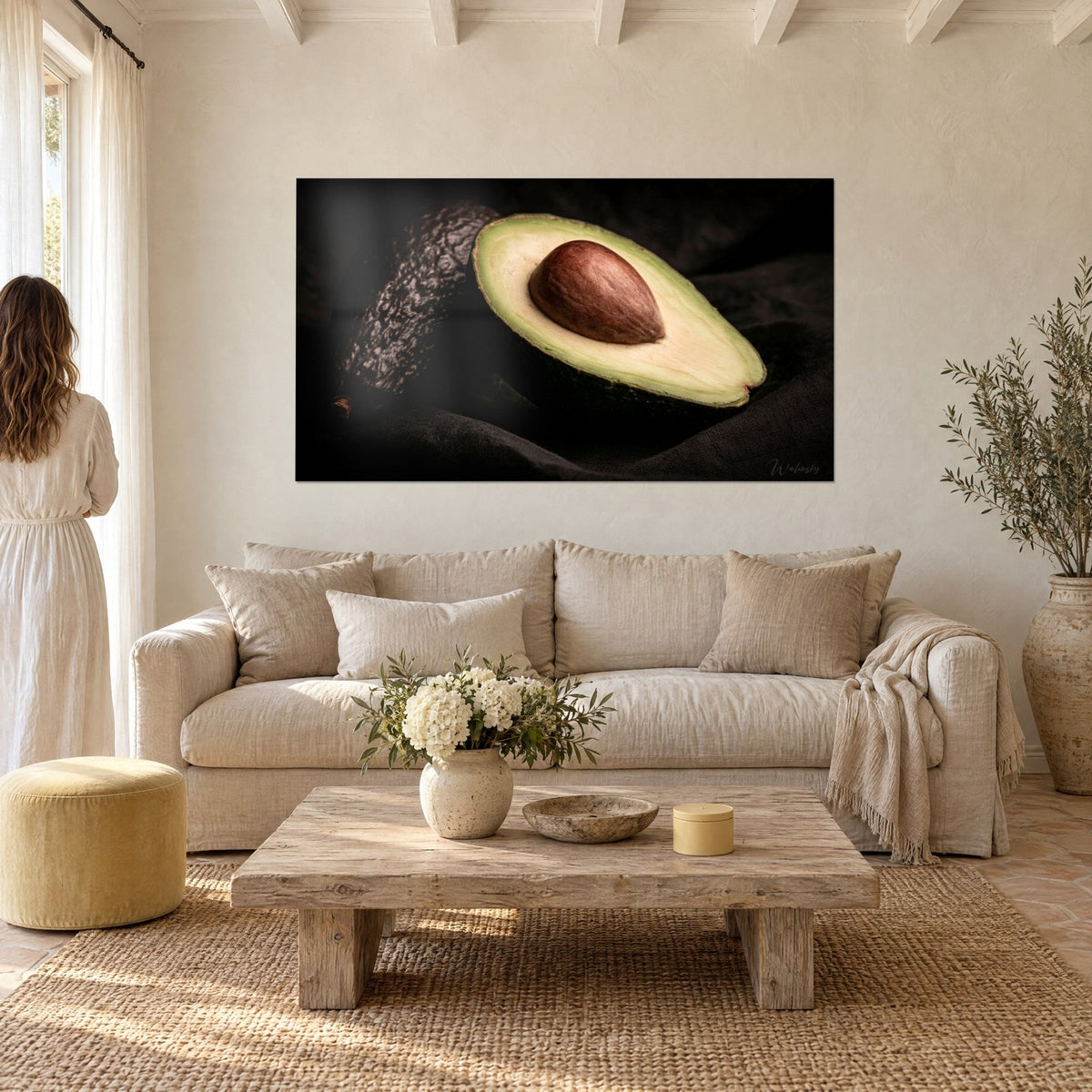 Tableau avocat ouvert à noyau brun luisant sur fond noir, chair vert tendre, couple de dos, au-dessus d'un canapé dans un salon lumineux