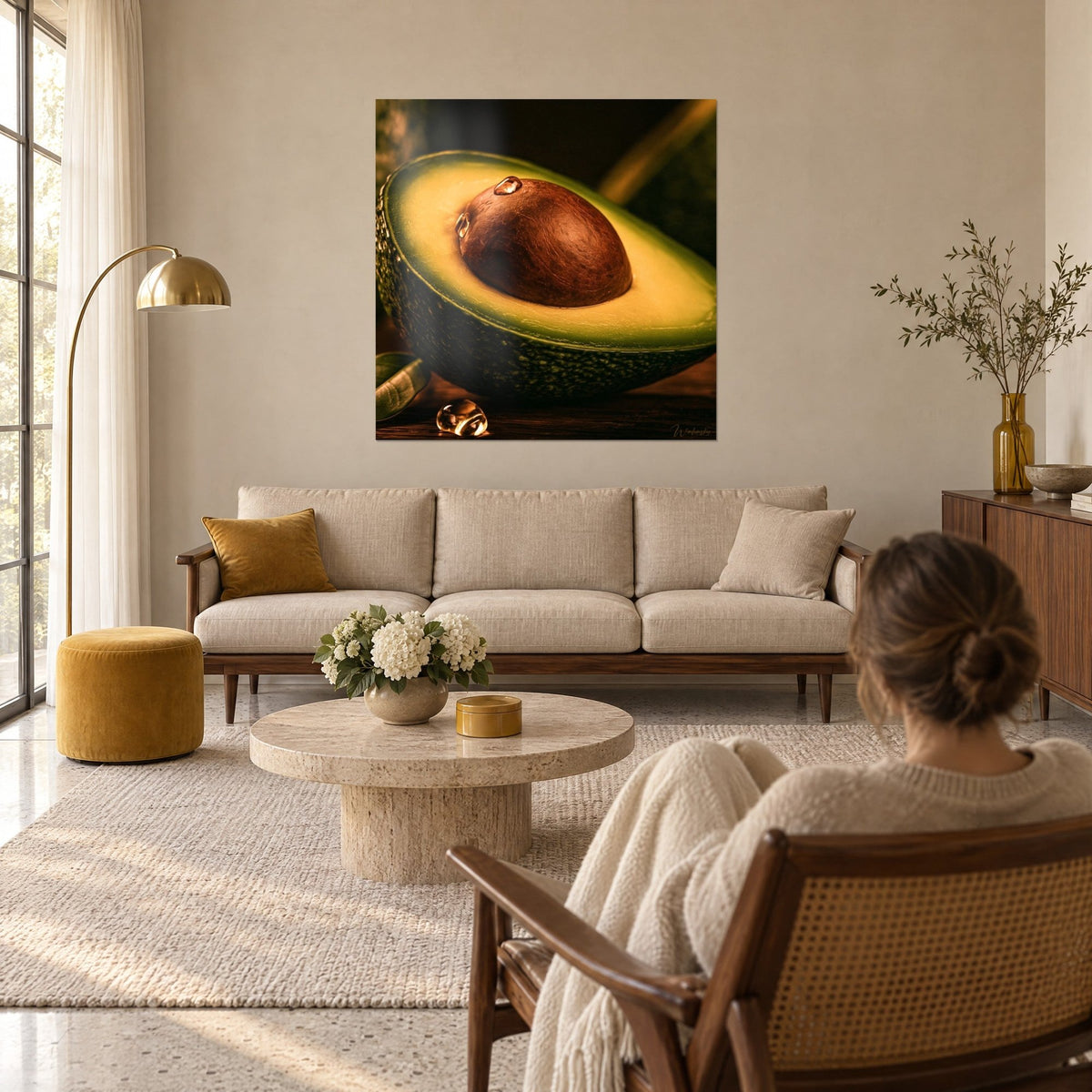 Quadro avocado tagliato, nocciolo bruno lucido e polpa verde dorata, di fronte a una donna di spalle, sopra un divano in un soggiorno luminoso