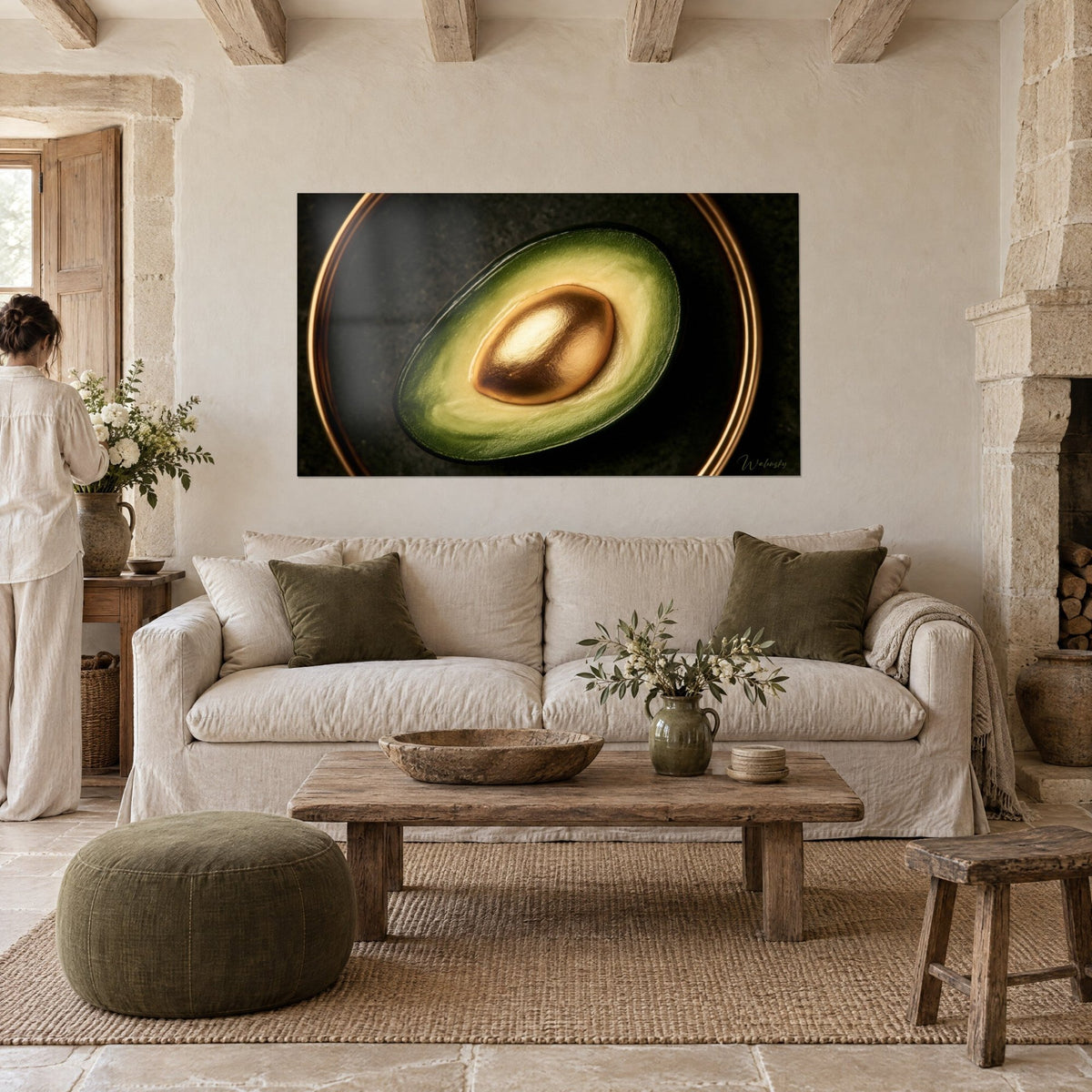 Schilderij avocado doormidden gesneden met gouden pit, zacht lichtgroen vruchtvlees omcirkeld met koper, twee personen met hun rug naar de kijker boven een bank in een lichte woonkamer