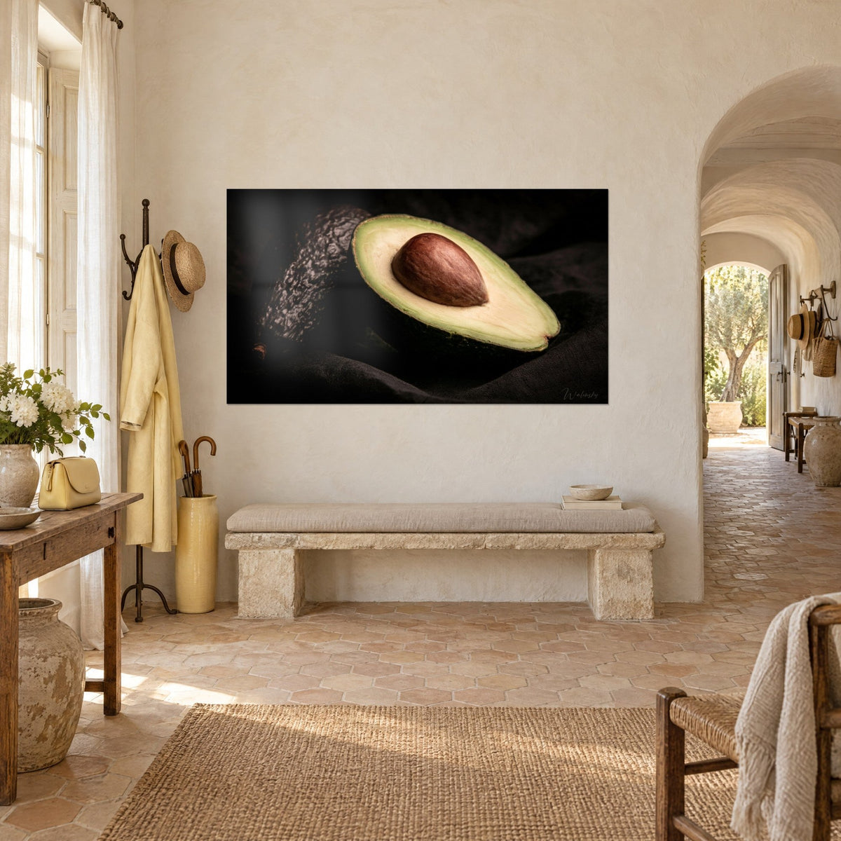Tableau demi-fruit crémeux et noyau acajou sur velours noir, peau vert sombre bosselée, mur blanc d'un mas provençal en vue de trois-quarts