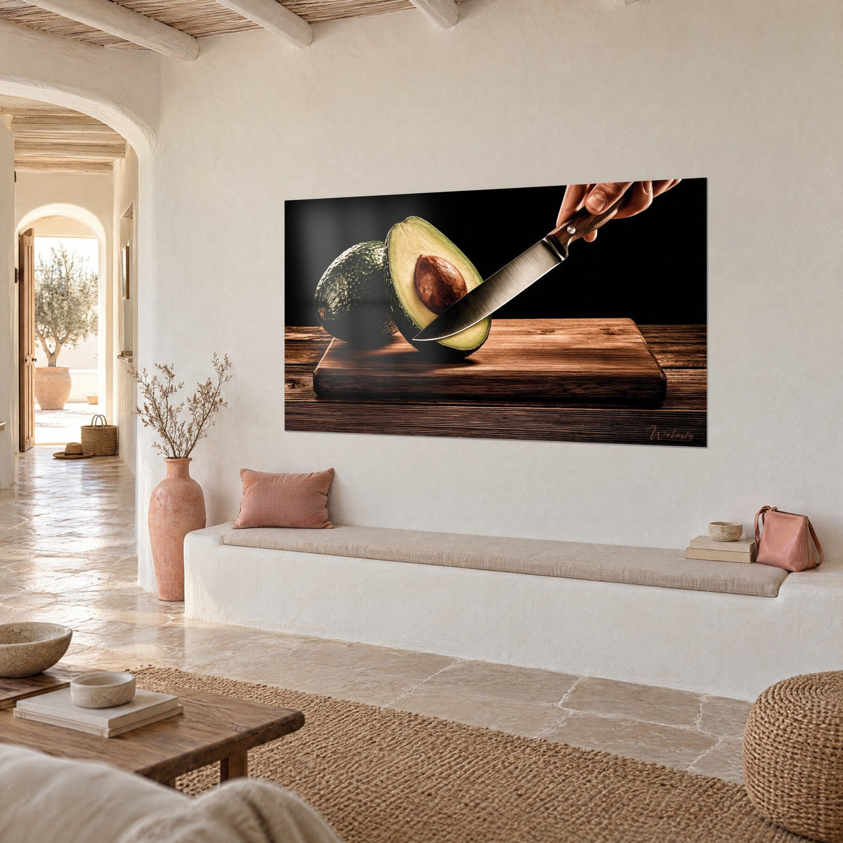 Wall art sliced green fruit, pale yellow flesh and silver knife, deep black background, hung in three-quarter view near a white banquette