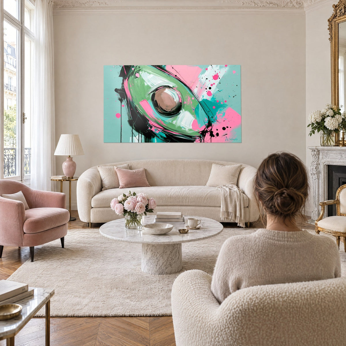 Tableau demi-avocat peint vert sauge et rose bonbon, noyau brun, éclaboussures noires, au-dessus d'un canapé dans un salon lumineux