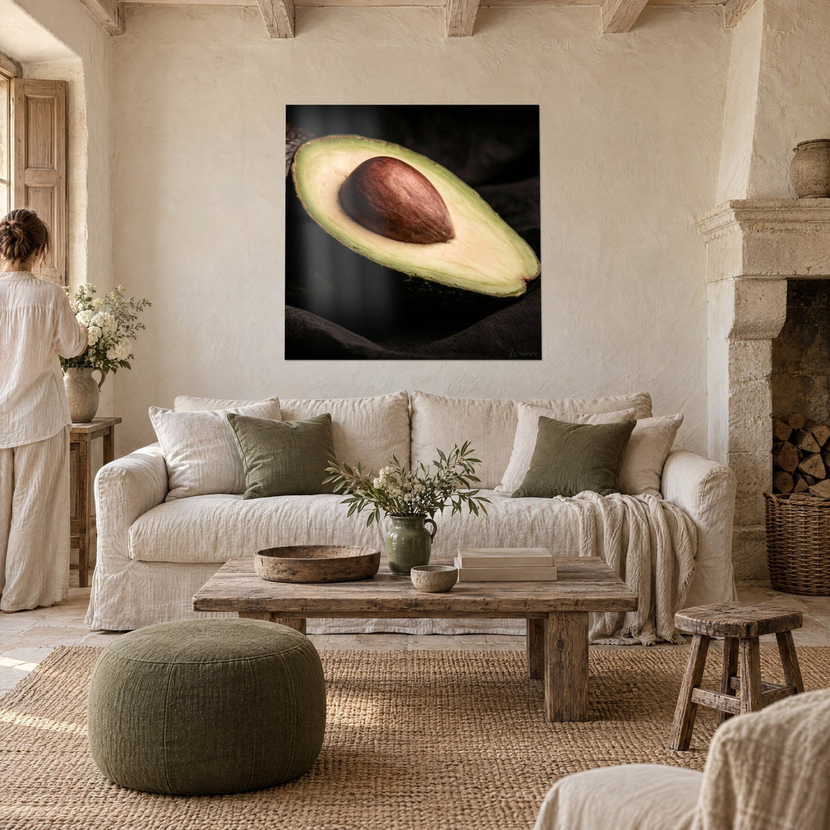 Wall art halved avocado with a glossy brown pit, soft green and cream flesh on a black background, hung above a sofa in a bright living room