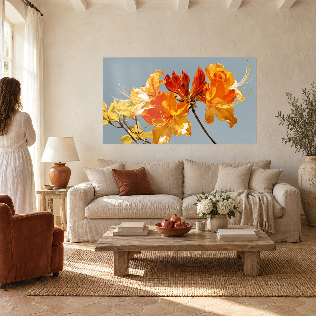 Tableau azalées orange vif aux étamines dorées sur fond gris bleuté, regardé de dos au-dessus d'un canapé dans un salon lumineux