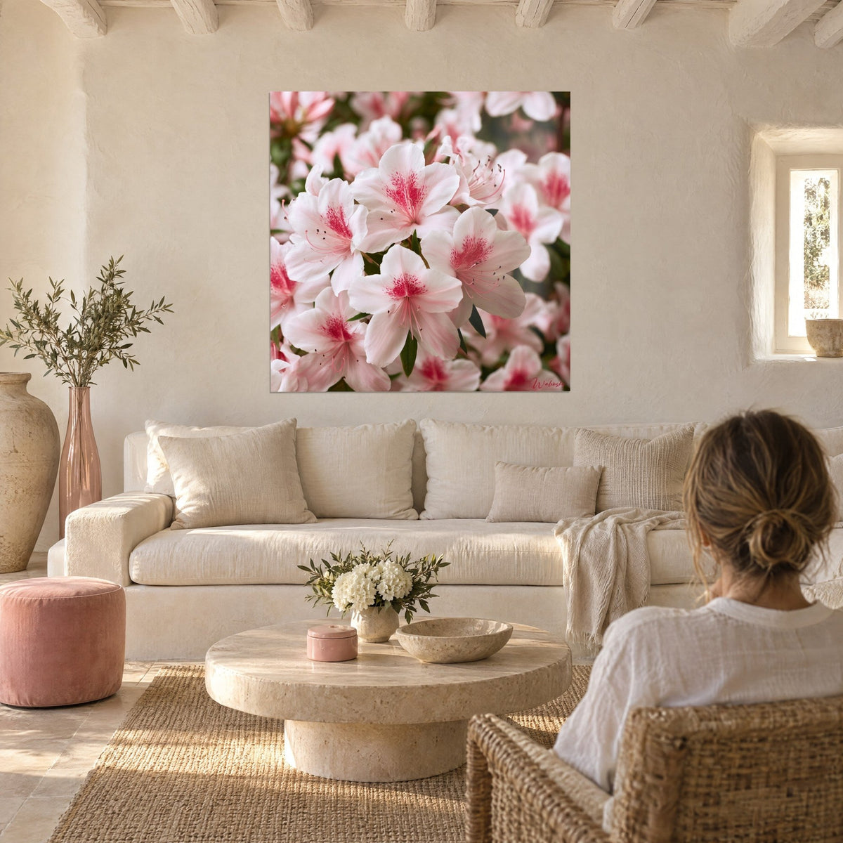 Wall art white azaleas with fuchsia pink hearts, woman seen from behind, cream walls, above a sofa in a bright living room