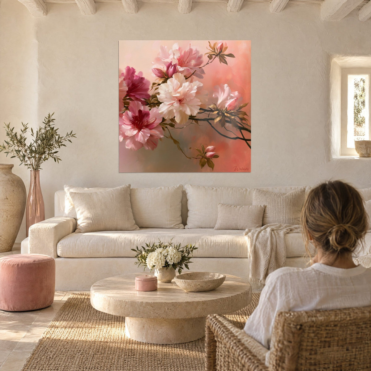 Tableau azalées rose poudré et blanc crème sur fond corail, une femme de dos au-dessus d'un canapé dans un salon lumineux