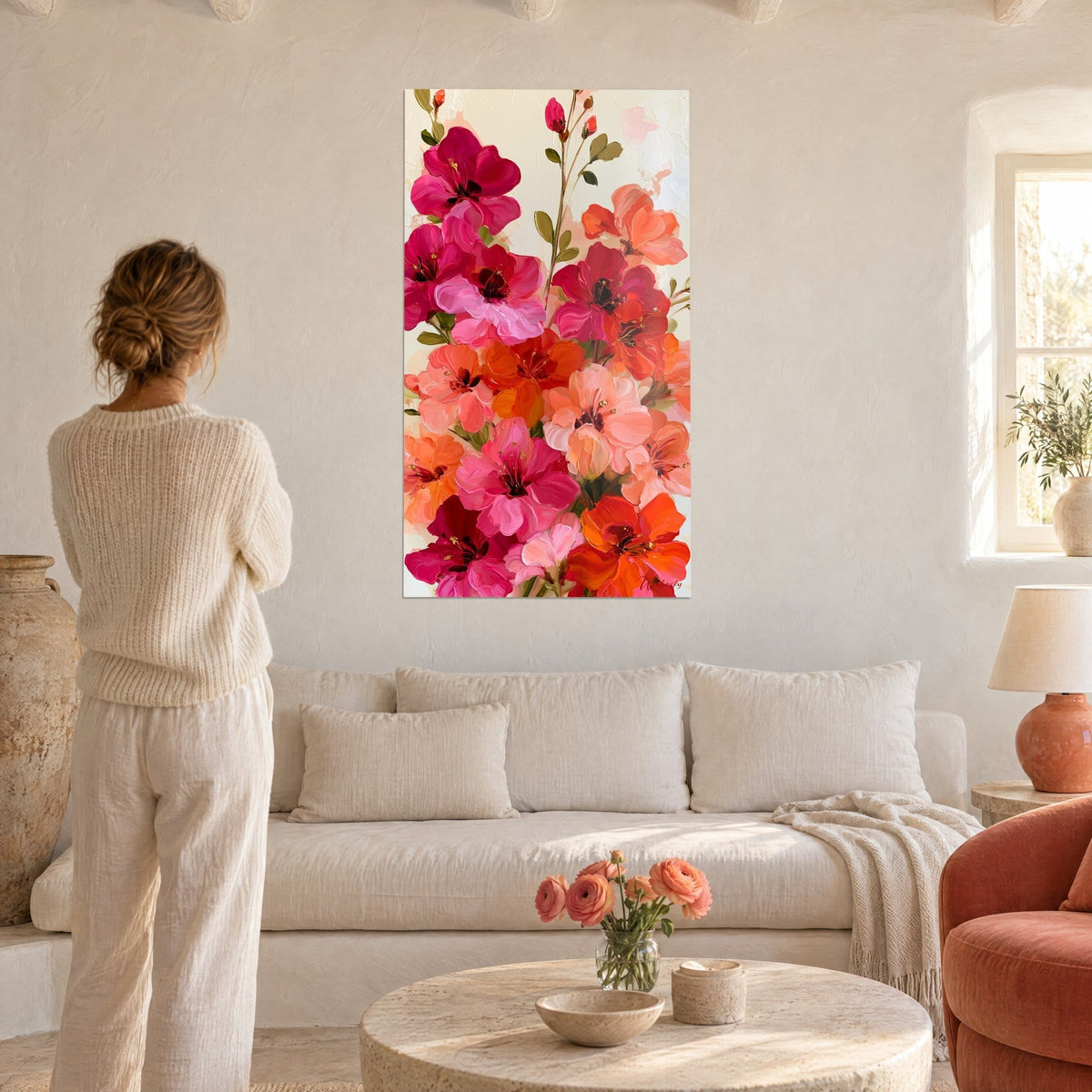 Tableau azalées magenta et orange peintes en empâtements, boutons verts en haut, une femme de dos, au-dessus d'un canapé dans un salon lumineux