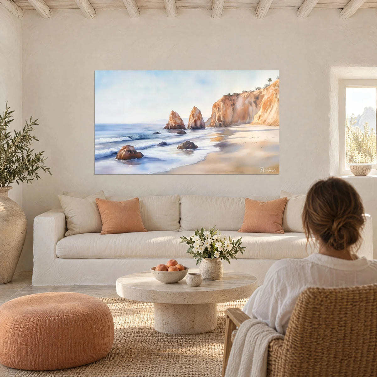 Gemälde einer ockerfarbenen Steilküste über einer Bucht, bläulicher Schaum auf dem Sand, über einem Sofa in einem hellen Wohnzimmer