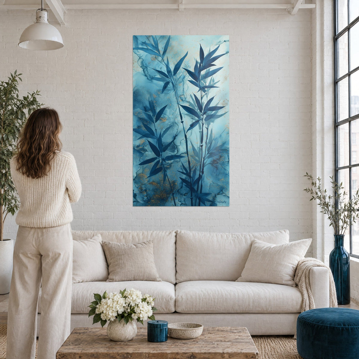 Tableau bambou bleu nuit sur fond turquoise marbré, paillettes dorées, femme de dos au-dessus d'un canapé dans un salon lumineux