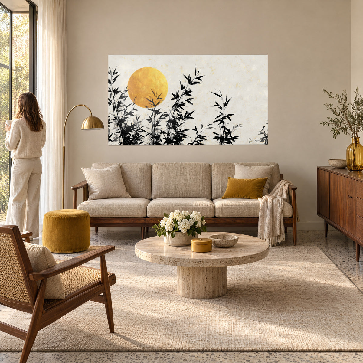 Quadro con disco dorato martellato dietro steli di bambù neri su fondo avorio, sopra un divano in un soggiorno luminoso