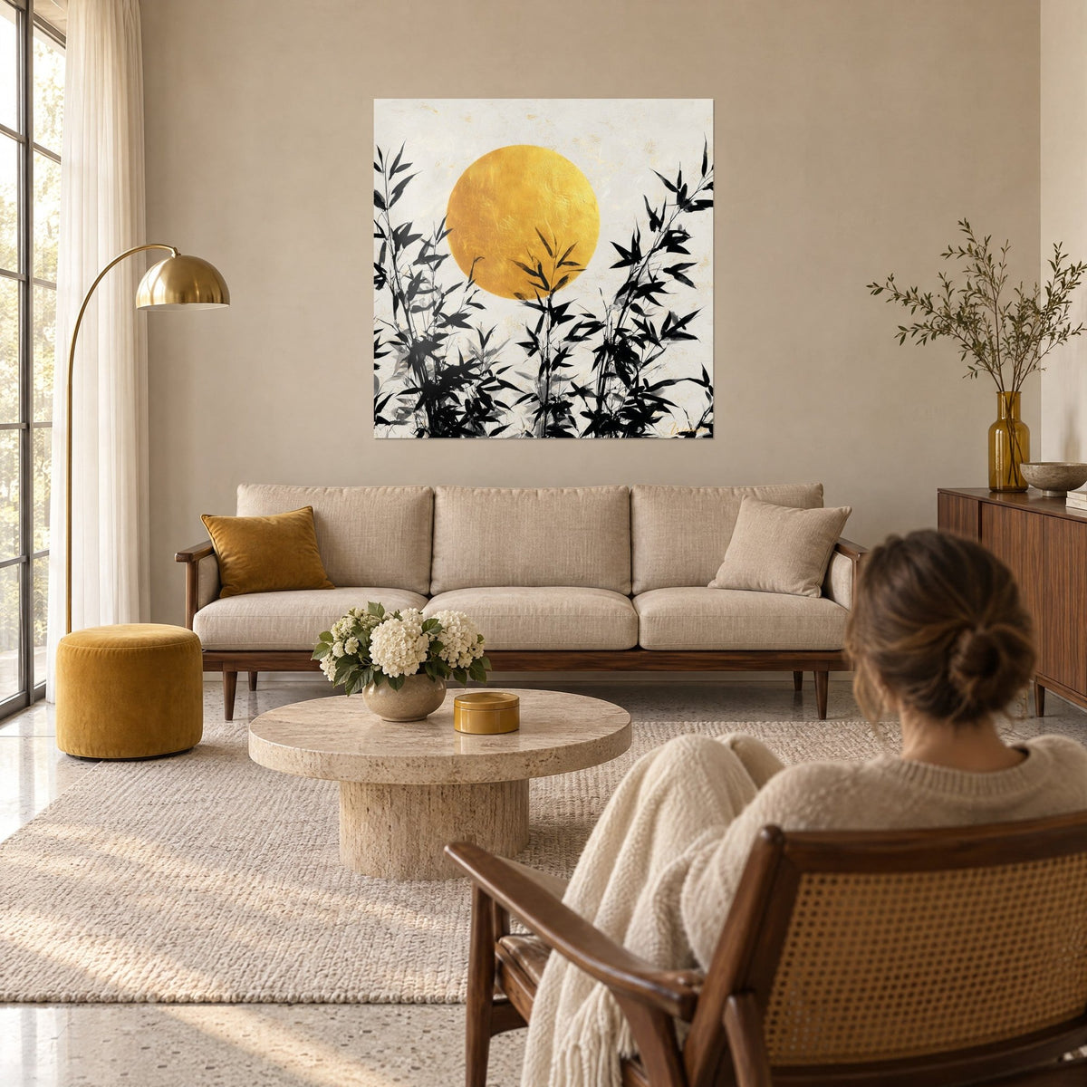 Tableau bambous noirs découpés sur un disque d'or, feuilles d'encre et fond crème, au-dessus d'un canapé dans un salon lumineux