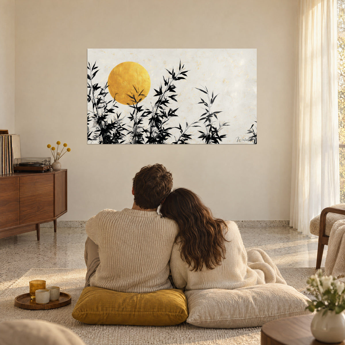 Quadro con grande disco ocra giallo e foglie di bambù nere su avorio, di fronte a una coppia seduta su cuscini crema, salotto