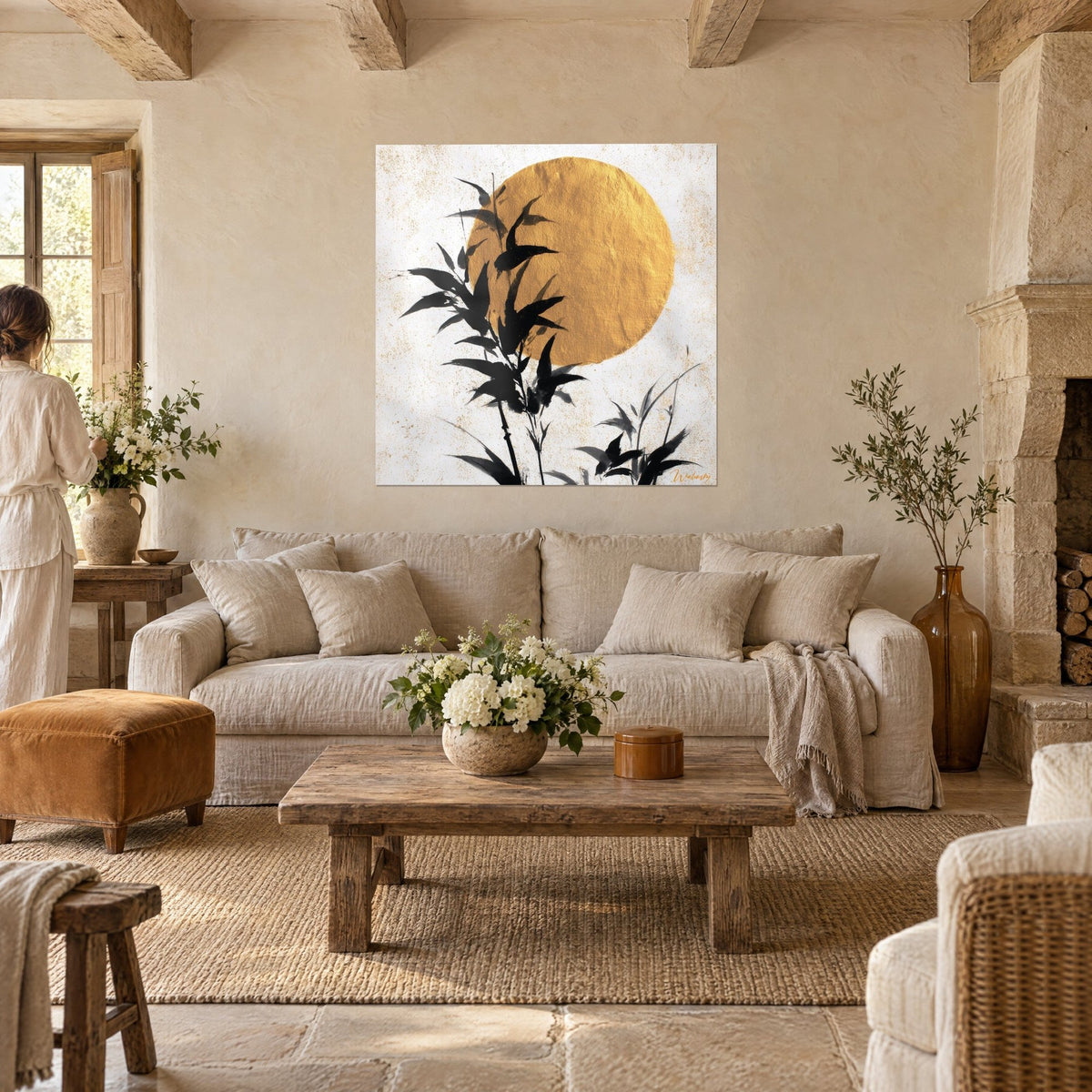 Tableau tiges de bambou à l'encre noire devant un grand disque doré texturé, tons crème, au-dessus d'un canapé dans un salon lumineux