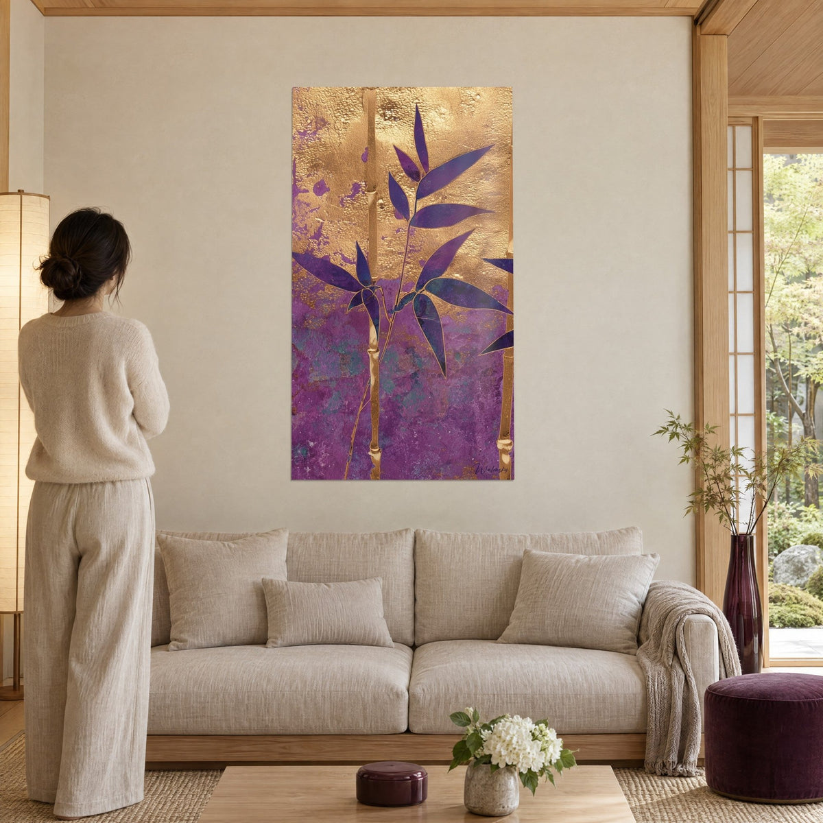 Tableau bambou aux feuilles pourpres sur fond doré martelé, tiges ocre et touches violettes, au-dessus d'un canapé dans un salon lumineux