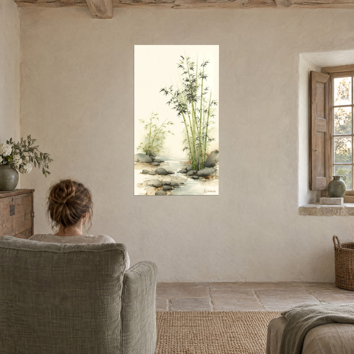 Wall art of a tuft of bamboo in green and cream wash, large gray rocks at the water's edge, a woman seen from behind in an armchair