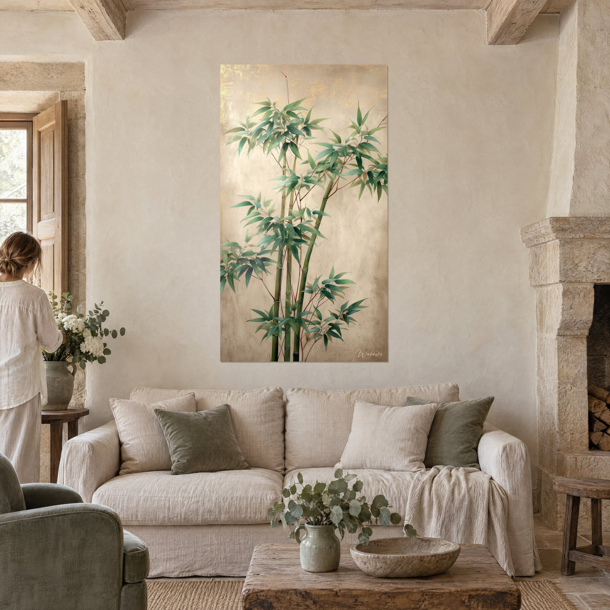 Tableau tiges de bambou vert jade sur fond beige doré patiné, femme de dos, au-dessus d'un canapé dans un salon lumineux