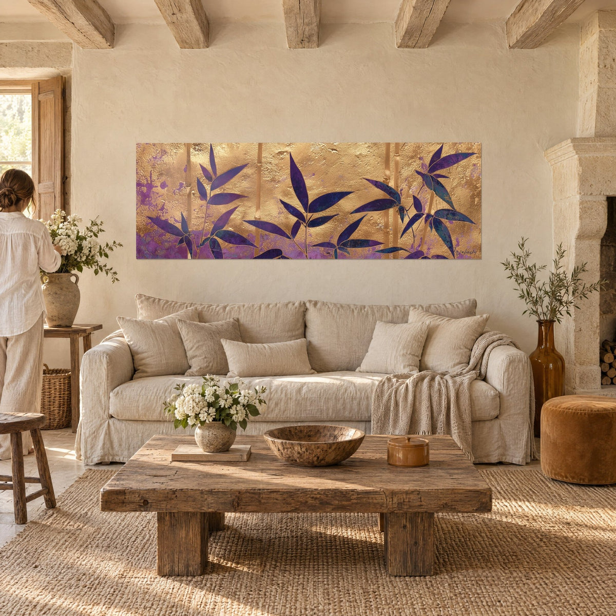 Tableau bambou doré aux feuilles indigo, fond d'or martelé et brumes violettes, au-dessus d'un canapé dans un salon lumineux